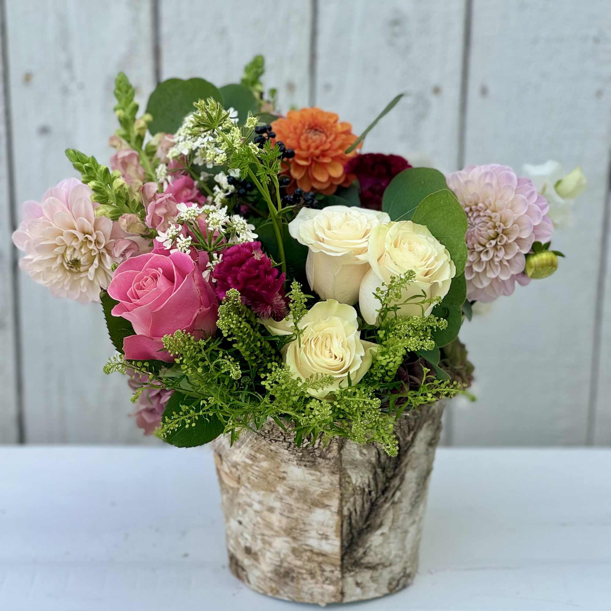 Mixed bouquet of roses and dahlias in a birch-style container