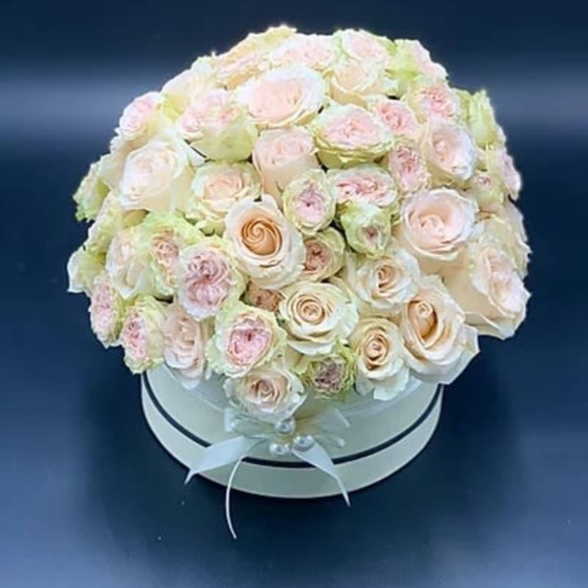 Round bouquet of pale pink and cream roses in a white hat box