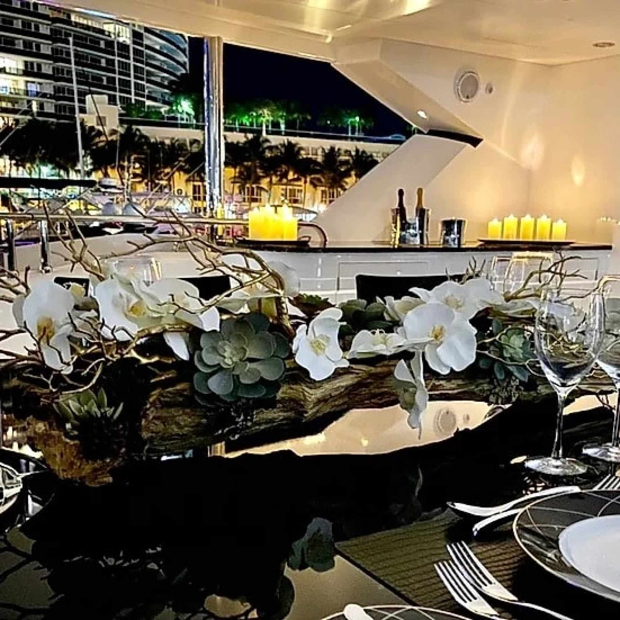 White orchid centerpiece with succulents and branches on a dining table