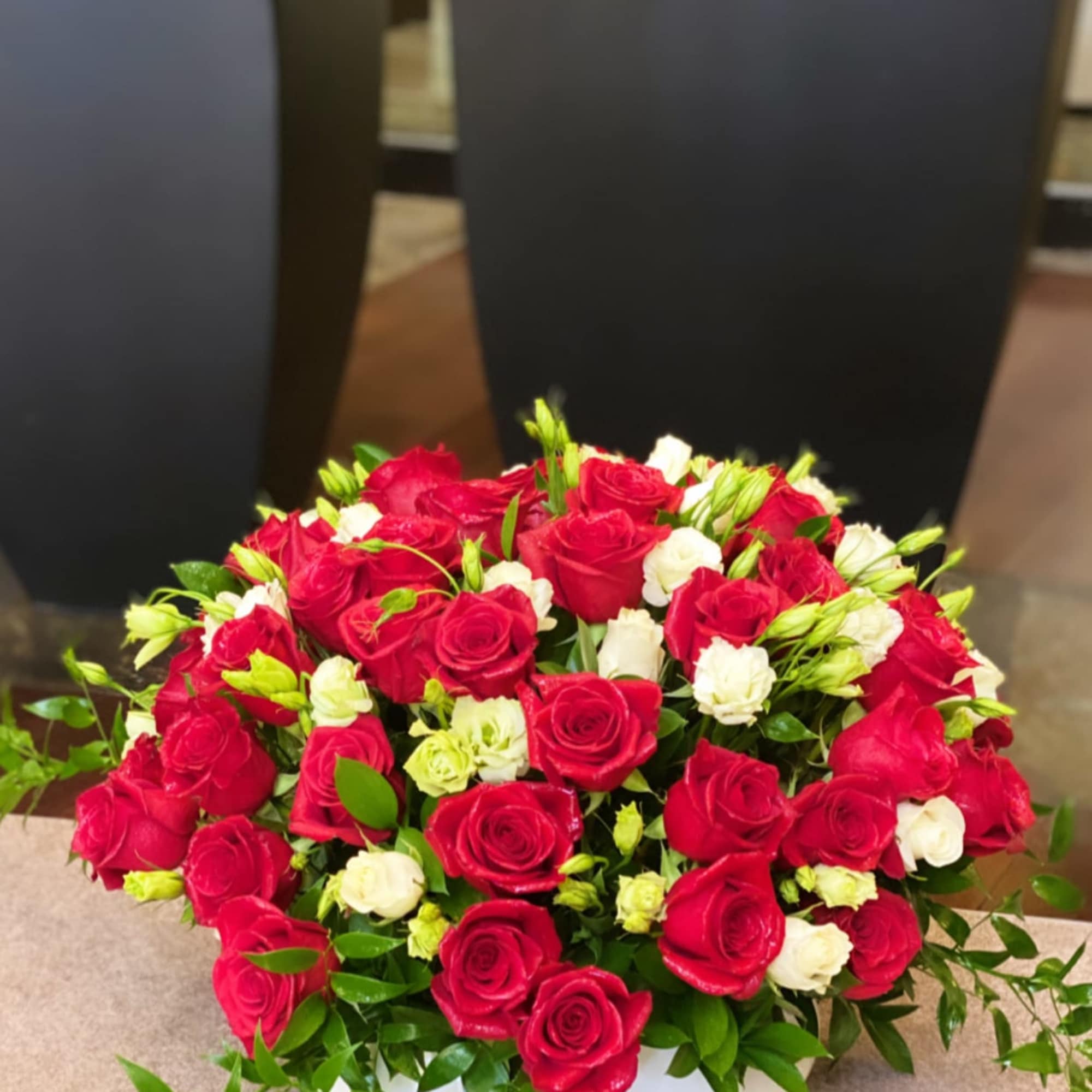 Red roses and white spray flowers in a low white bowl