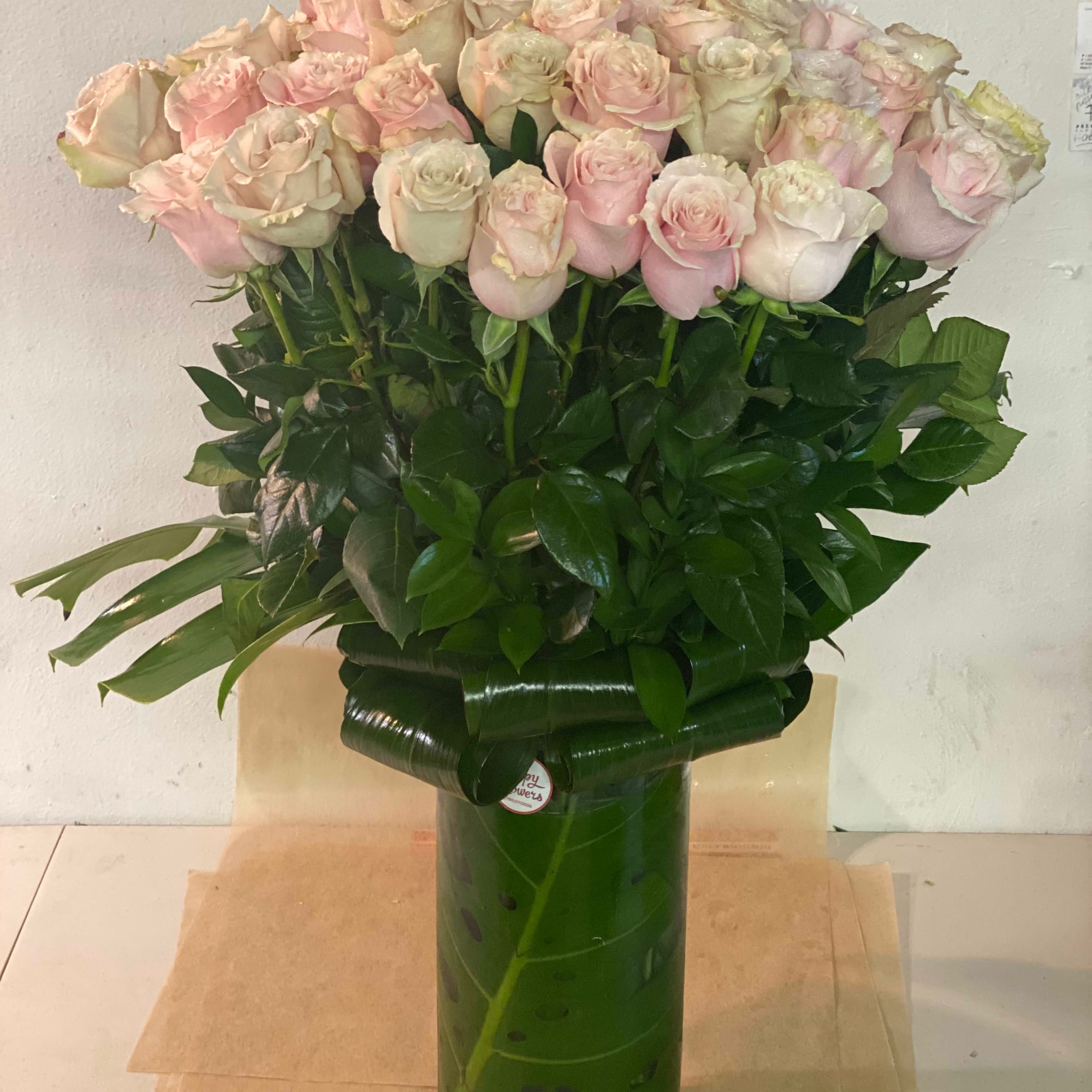 Bouquet of pale pink and cream roses in a tall green vase
