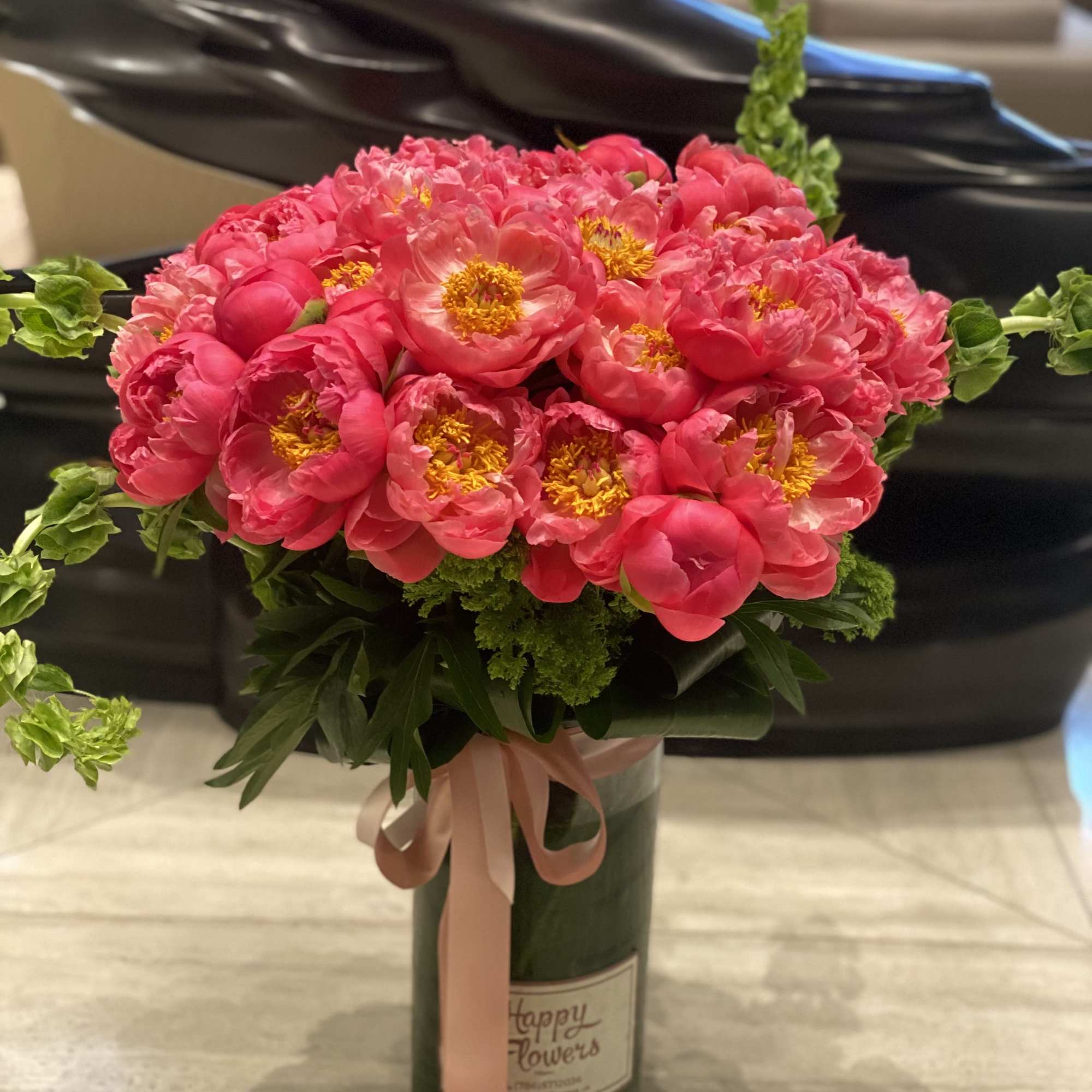 Pink peony bouquet in a green vase with a pink ribbon