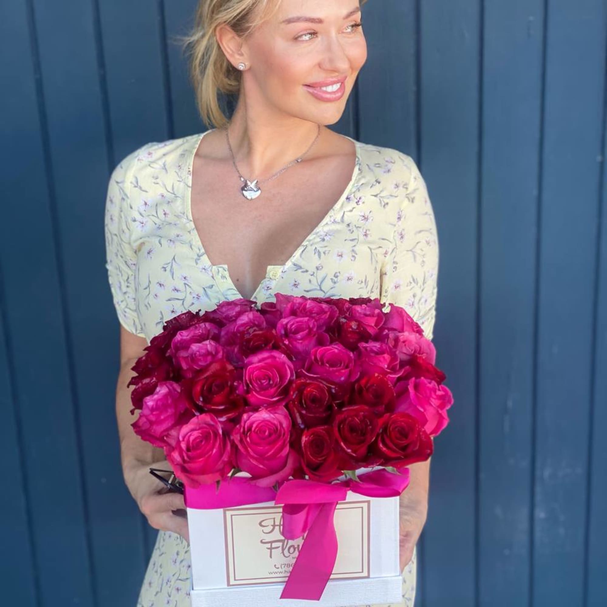 Woman holding a box of bright pink and red roses with a ribbon