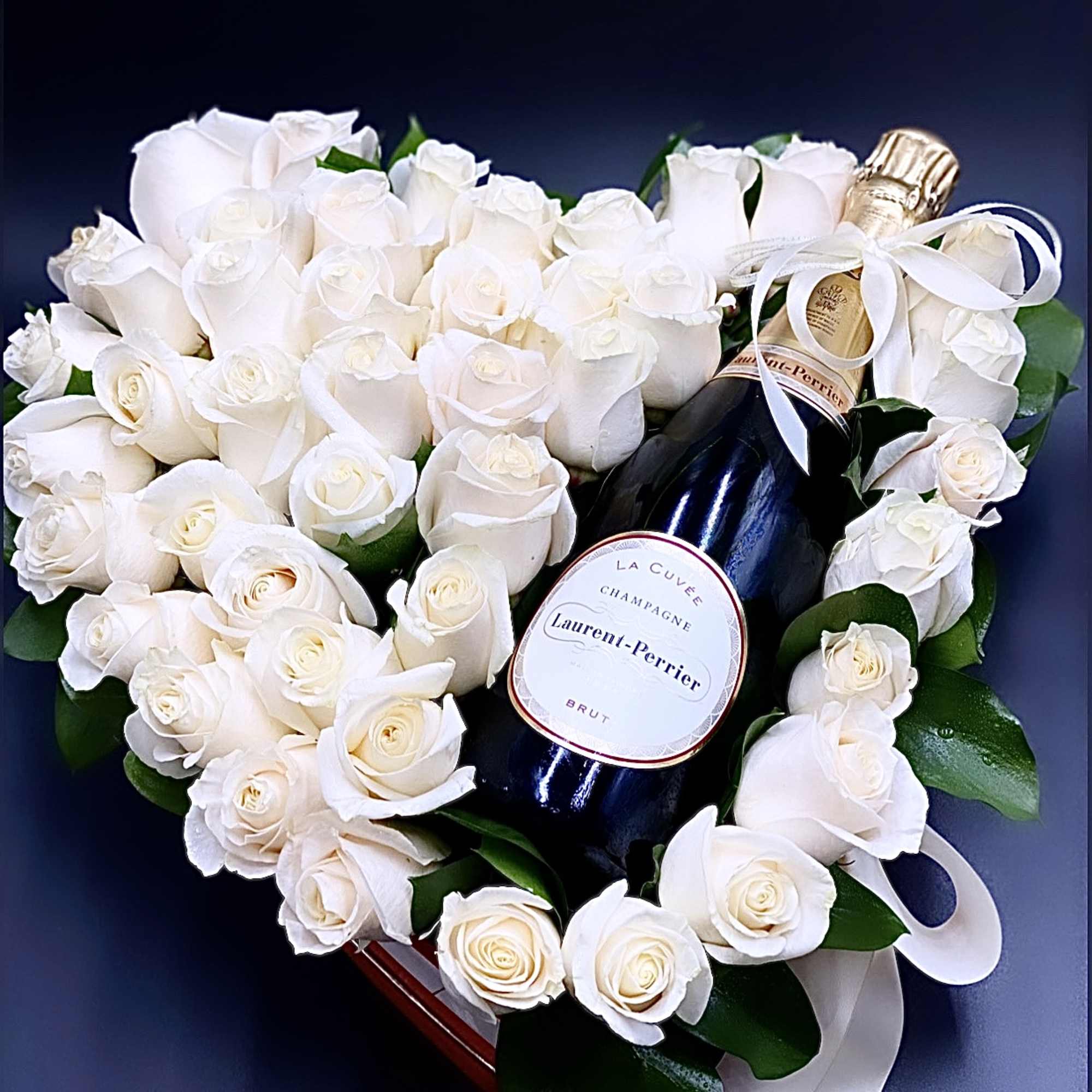 Heart-shaped white rose arrangement with a champagne bottle and ribbon