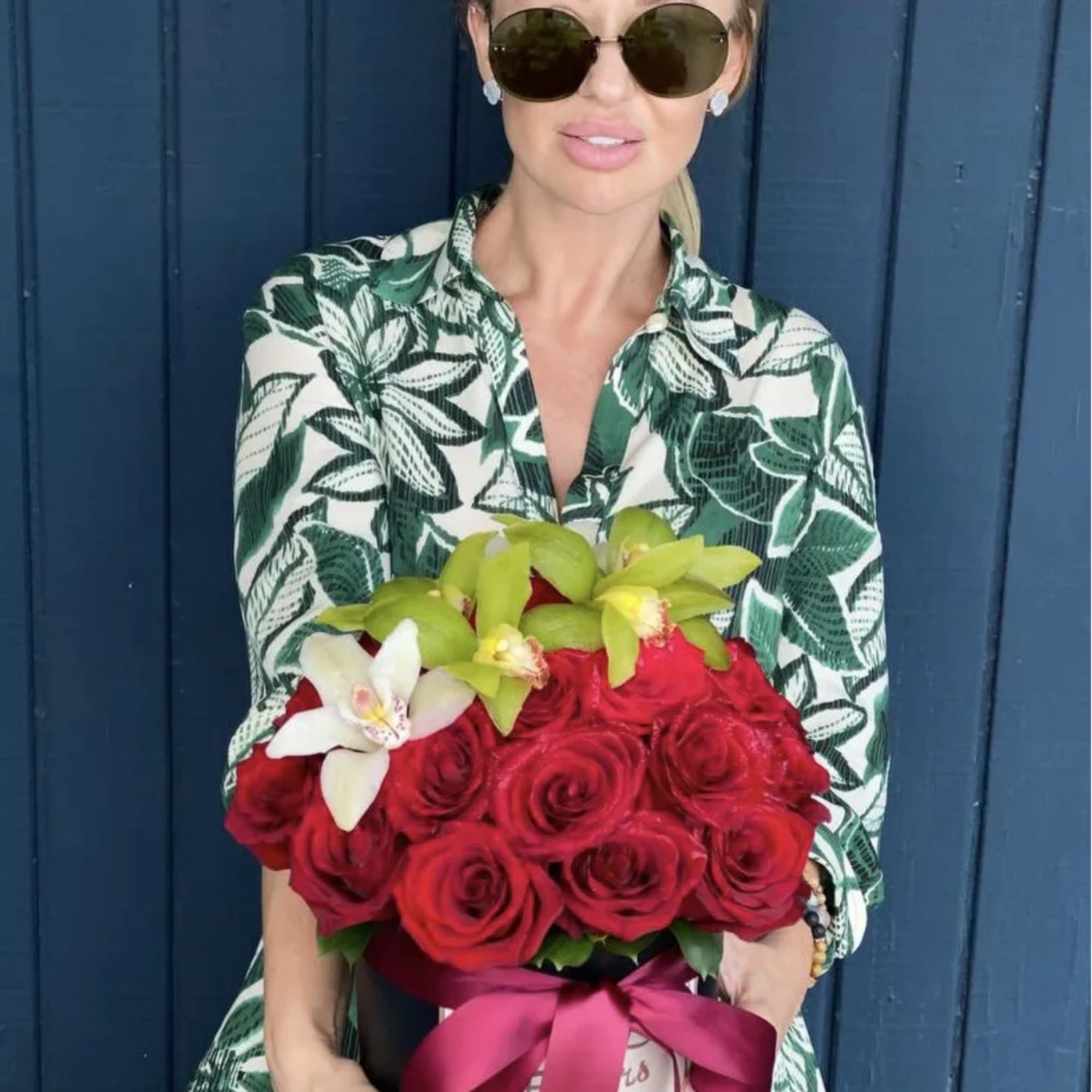 Woman holding a box of red roses with white and green orchids