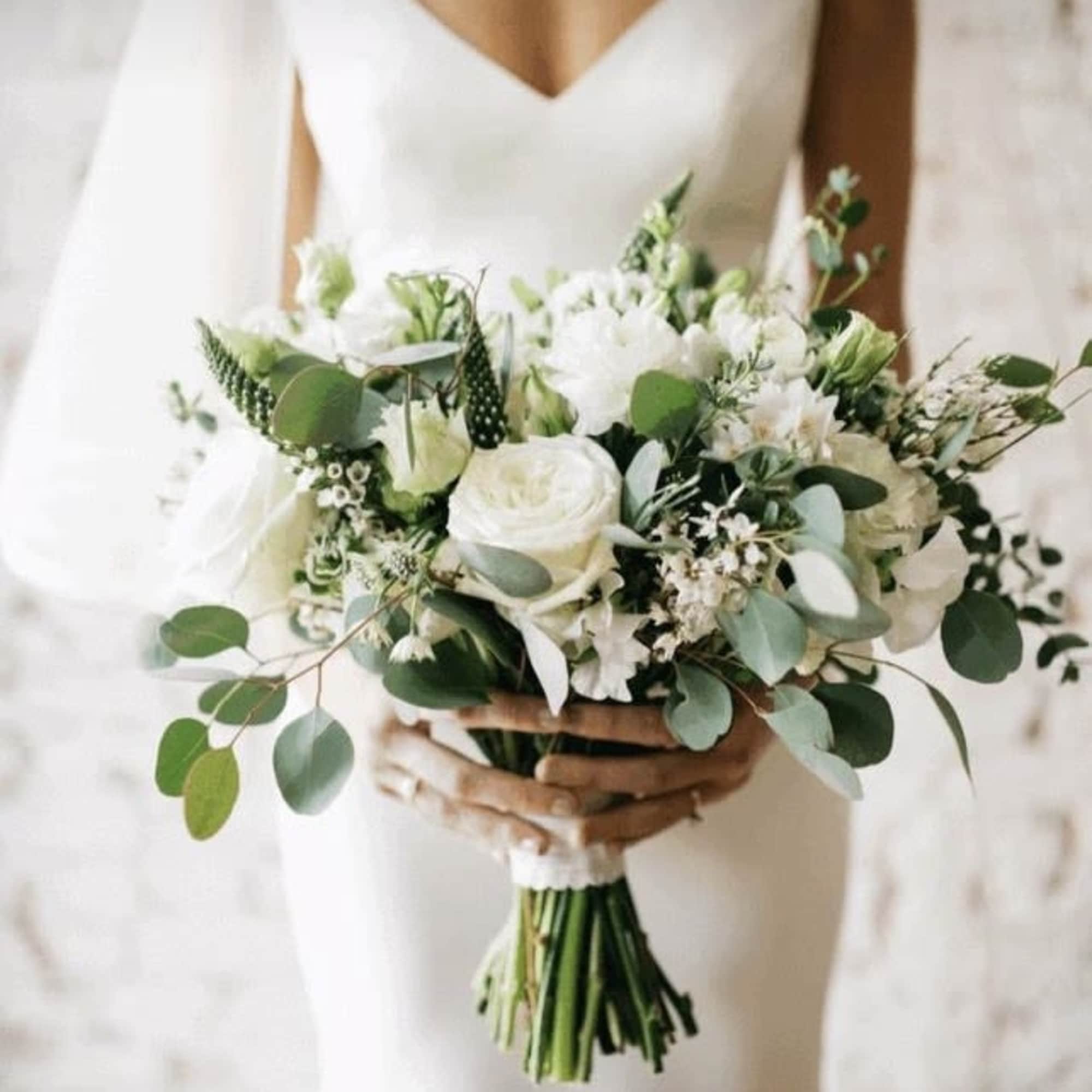 Bride holding a white and green bouquet with roses and mixed blooms
