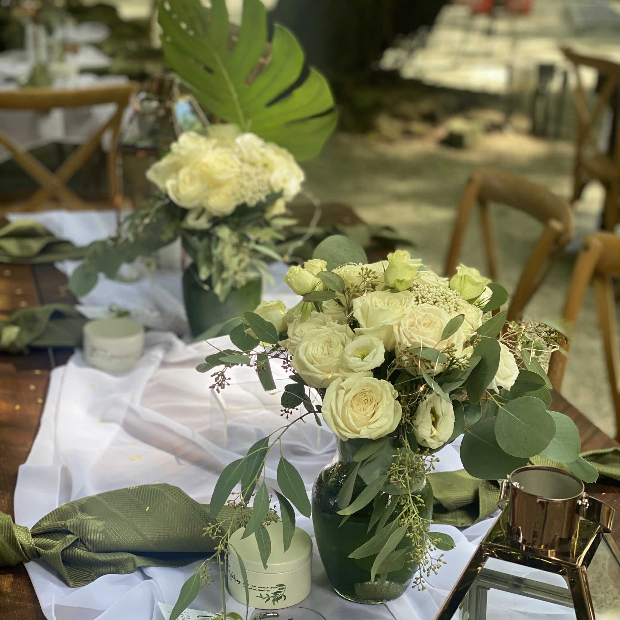 White rose arrangements in green vases on a decorated table