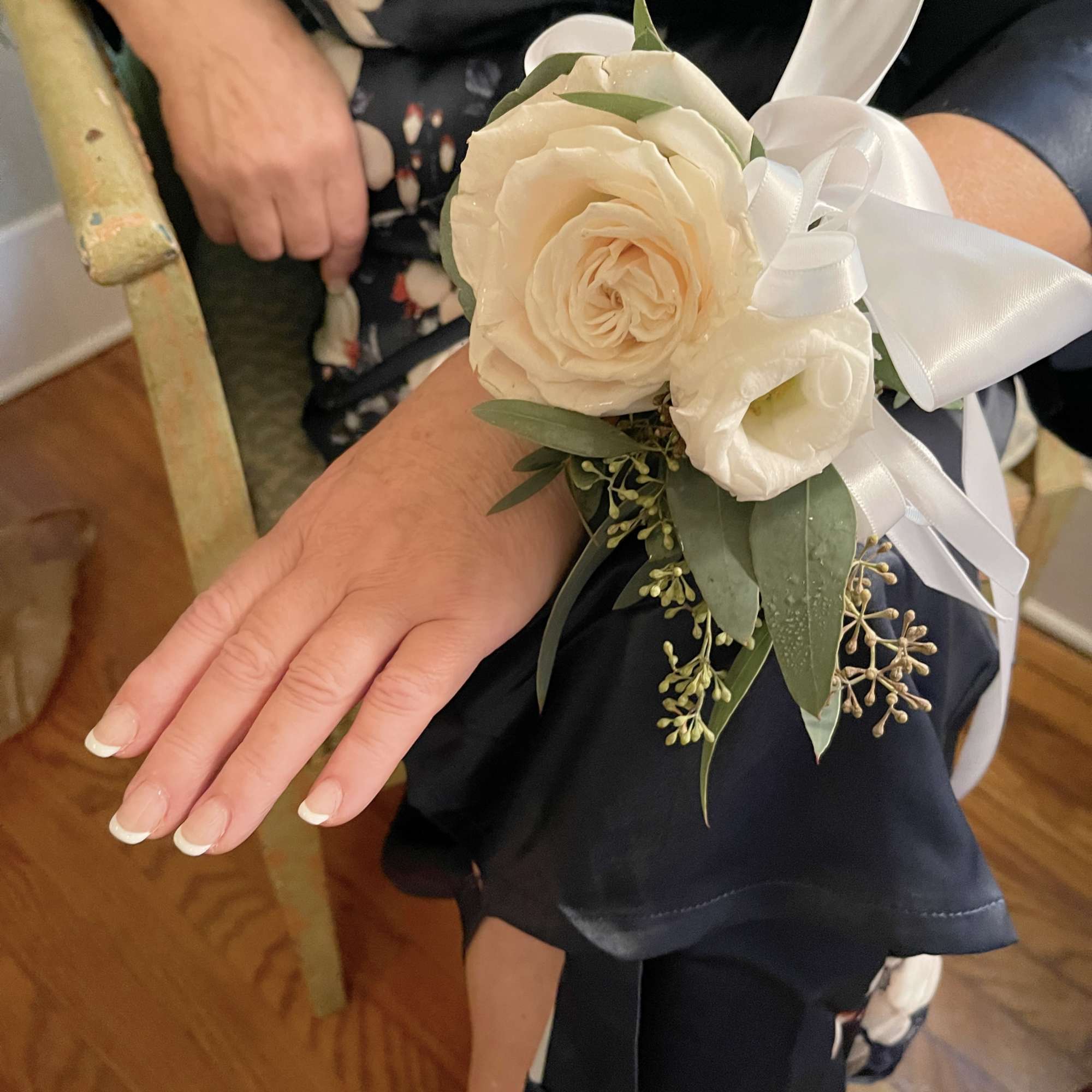 Cream rose wrist corsage with white ribbon and greenery