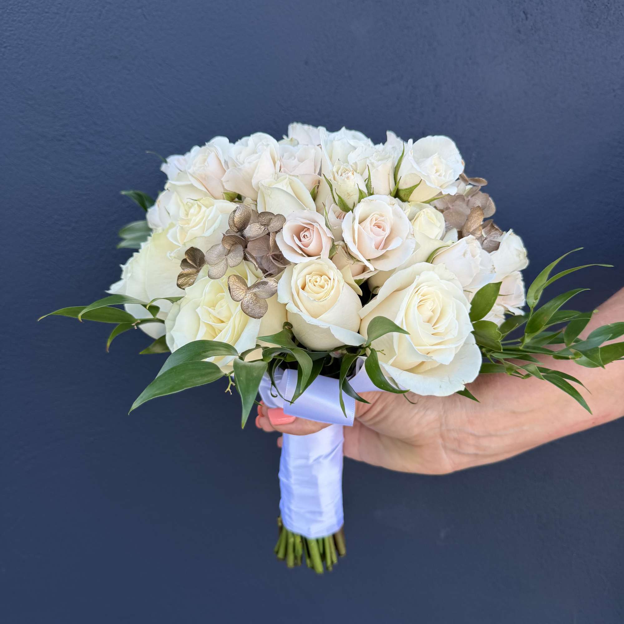 White rose bridal bouquet with pale pink accents and greenery