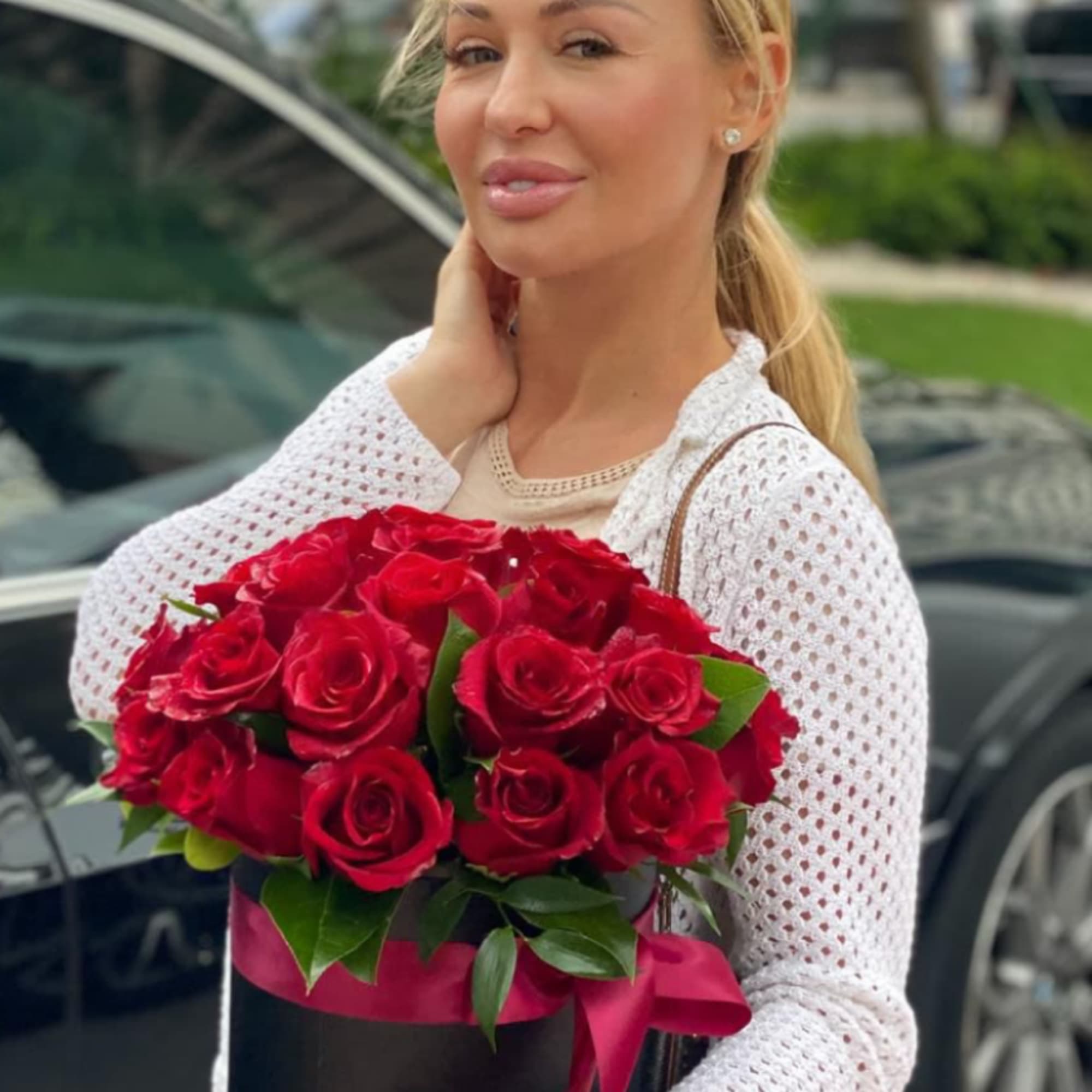 Woman holding a box of red roses tied with a pink ribbon