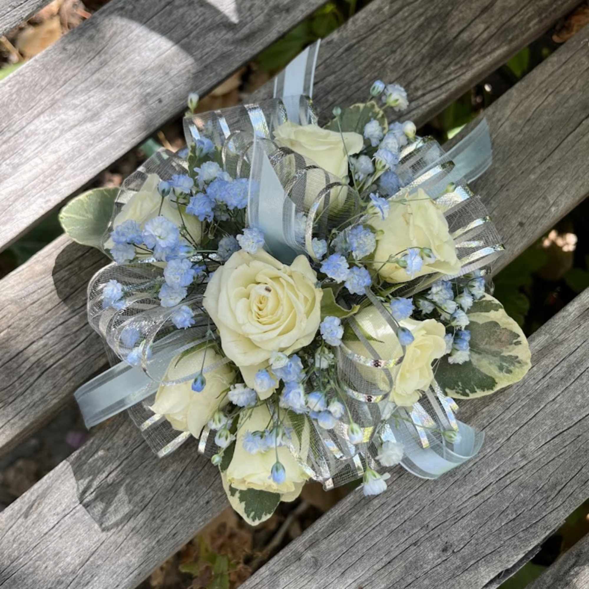 Small bouquet of cream roses and blue filler flowers with ribbon