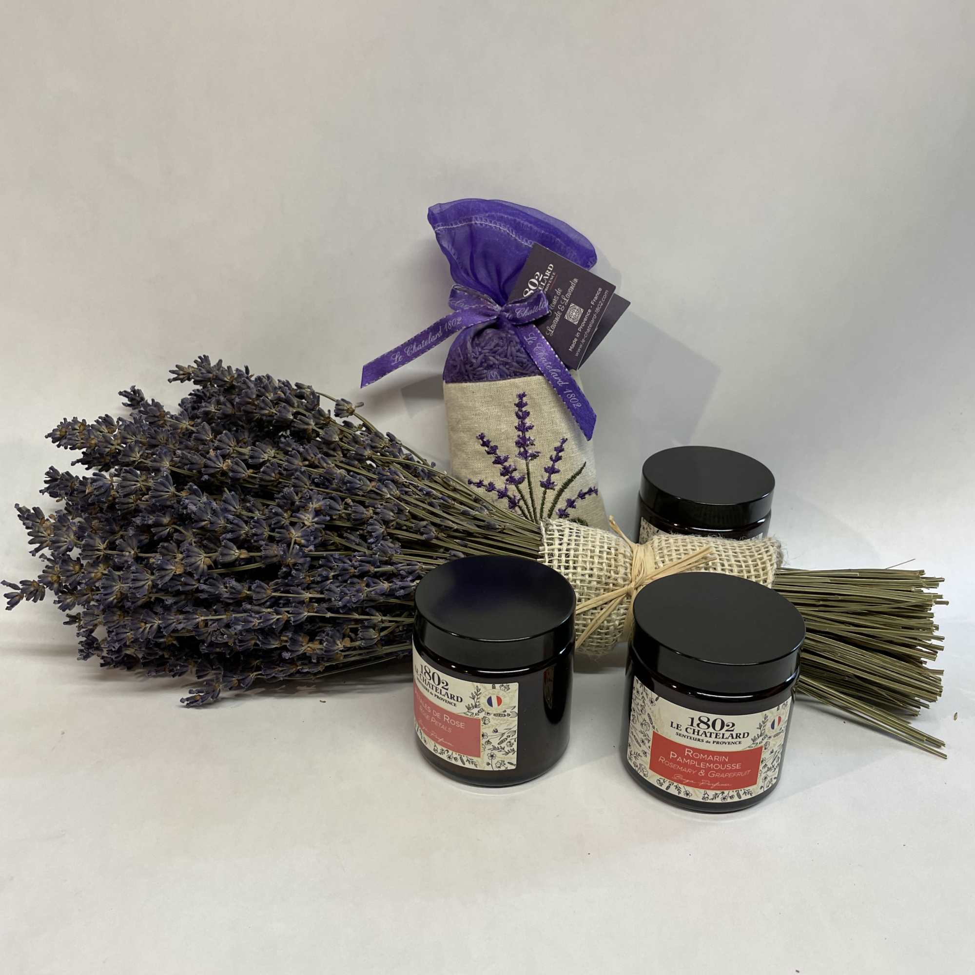 Bundle of dried lavender with three black-lidded jars and a purple sachet