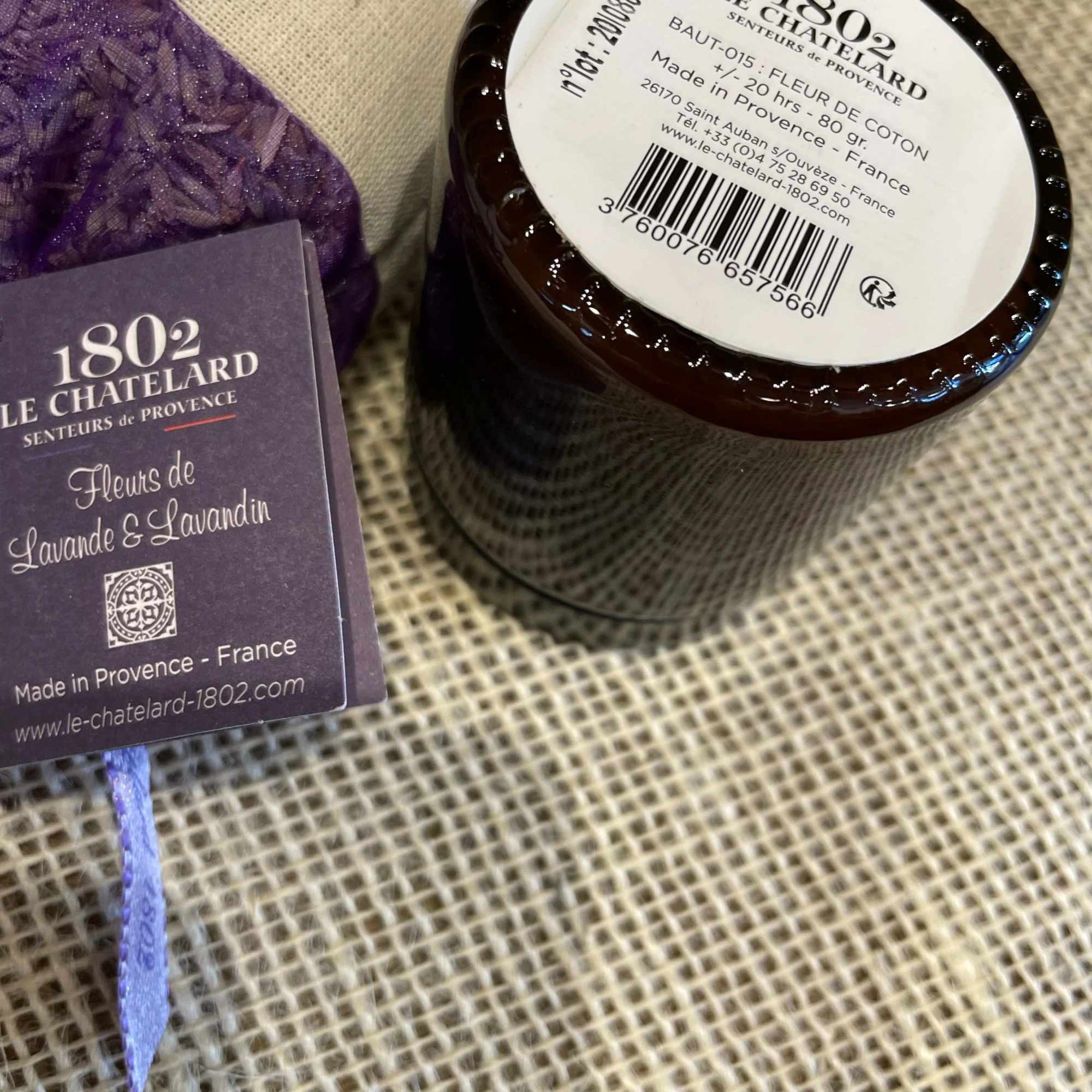 Lavender-scented candle jar with a purple fabric sachet and tag