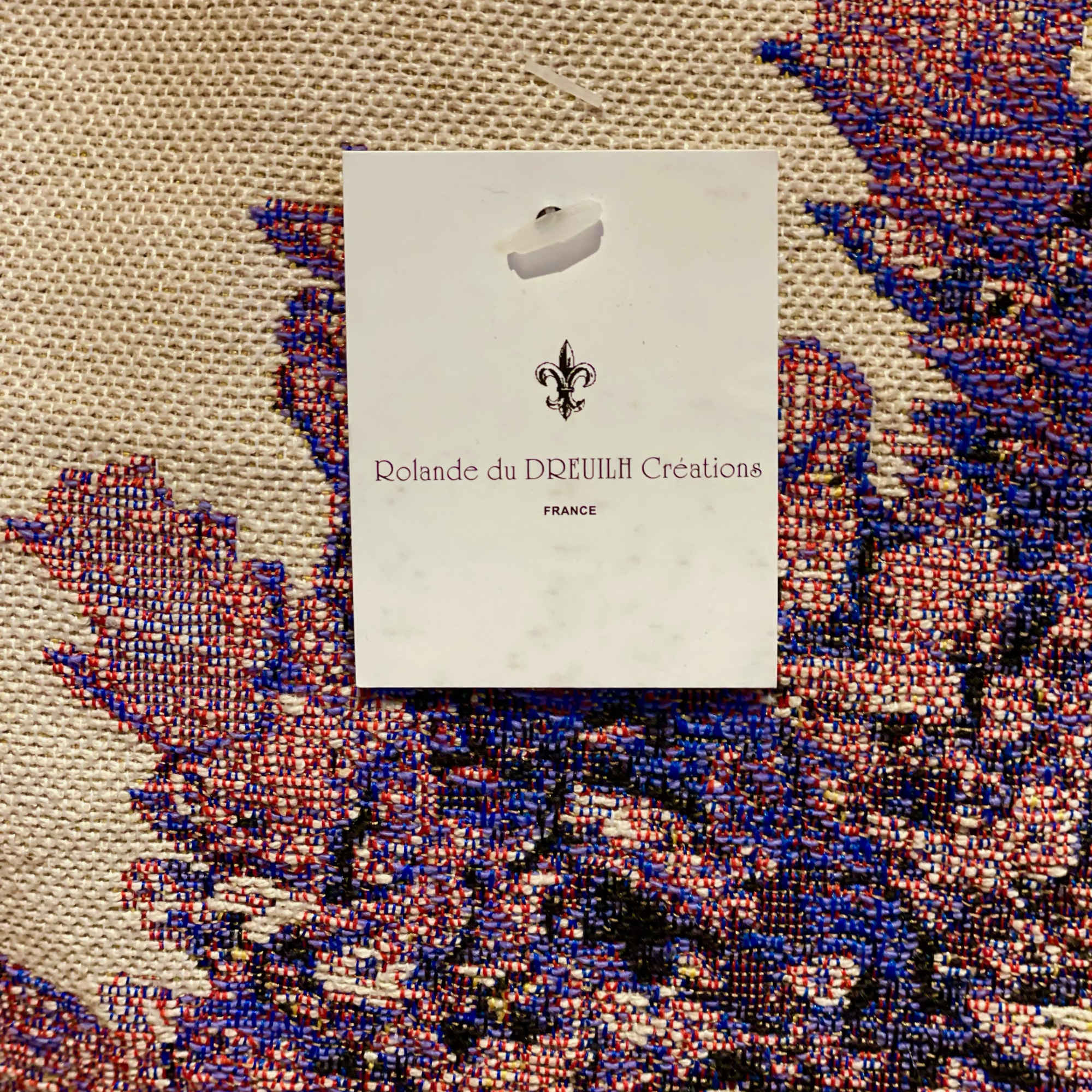 White product tag on a woven red, blue, and beige textile