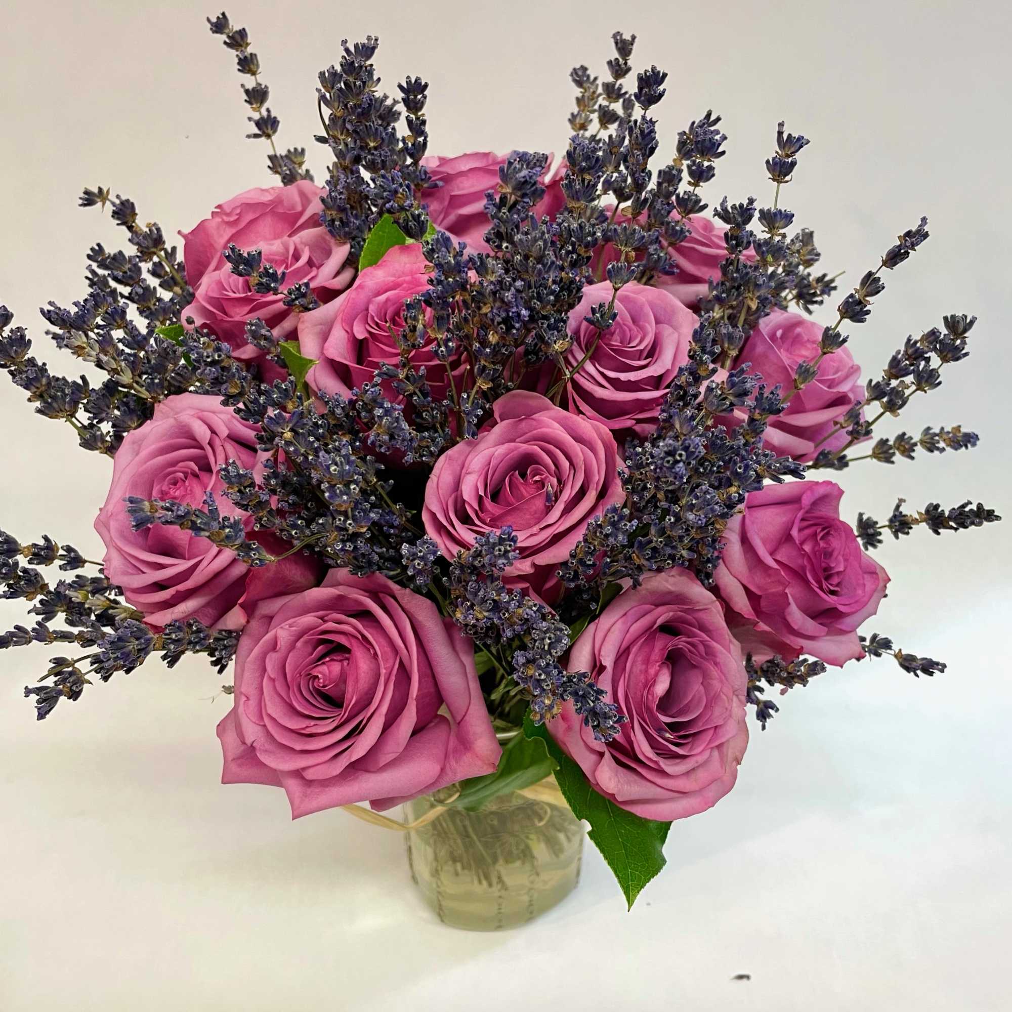 Pink roses arranged with purple lavender in a clear glass vase