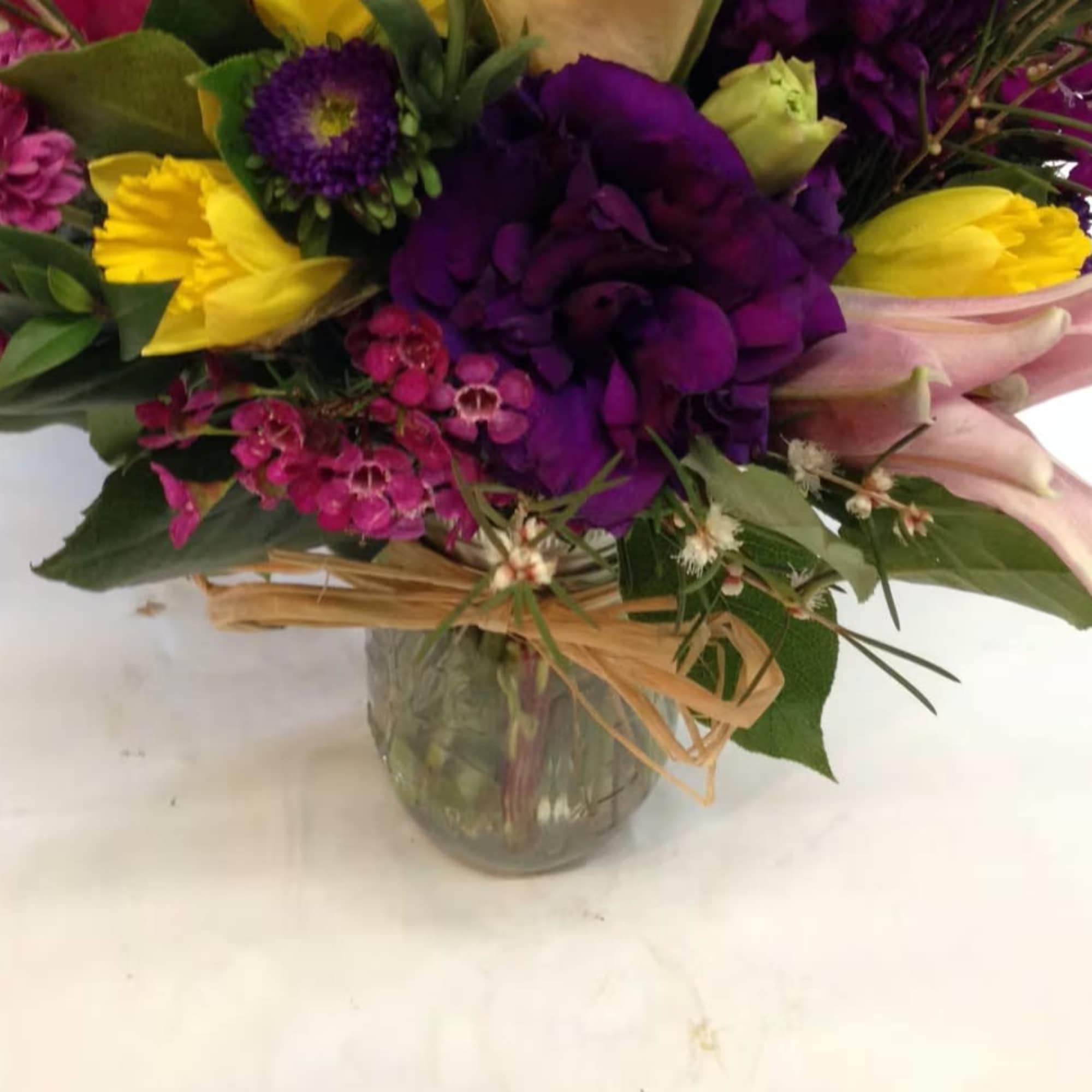 Mixed bouquet of purple, pink, and yellow flowers in a glass vase