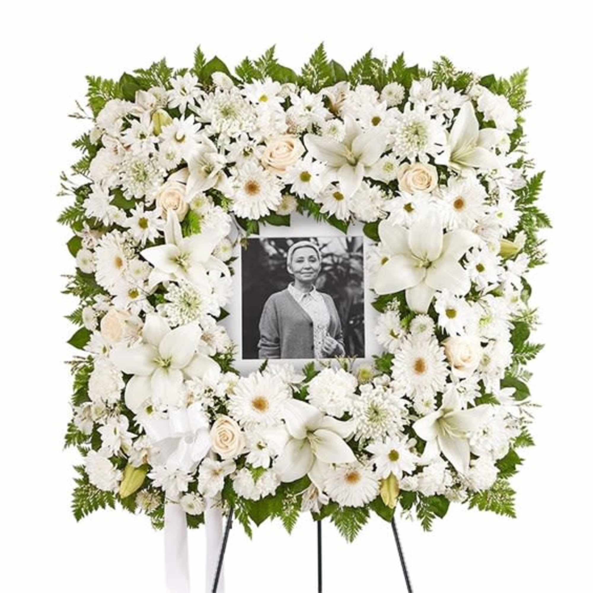 White funeral wreath with a photo in the center on a stand