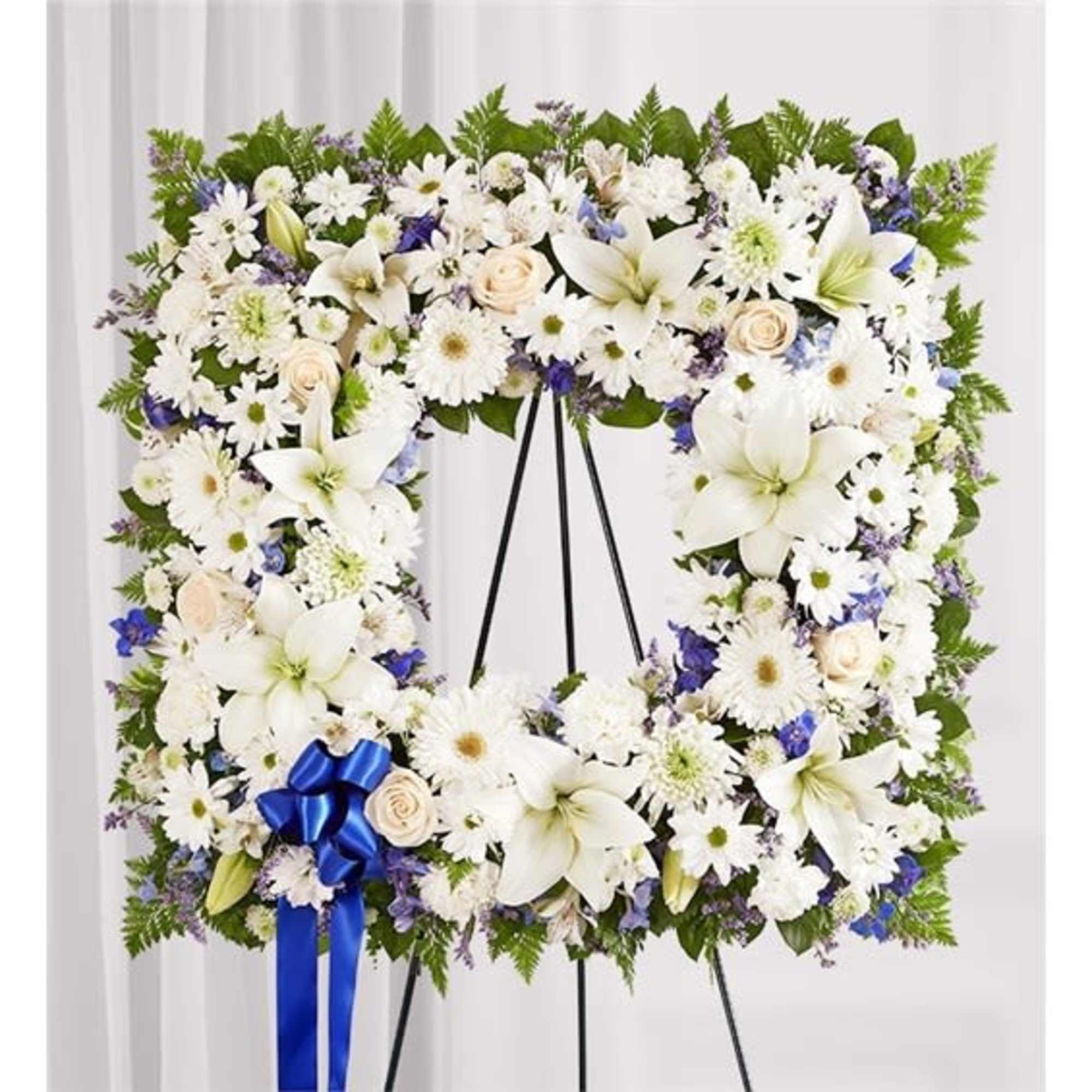 Large white floral wreath on a black stand with a blue ribbon
