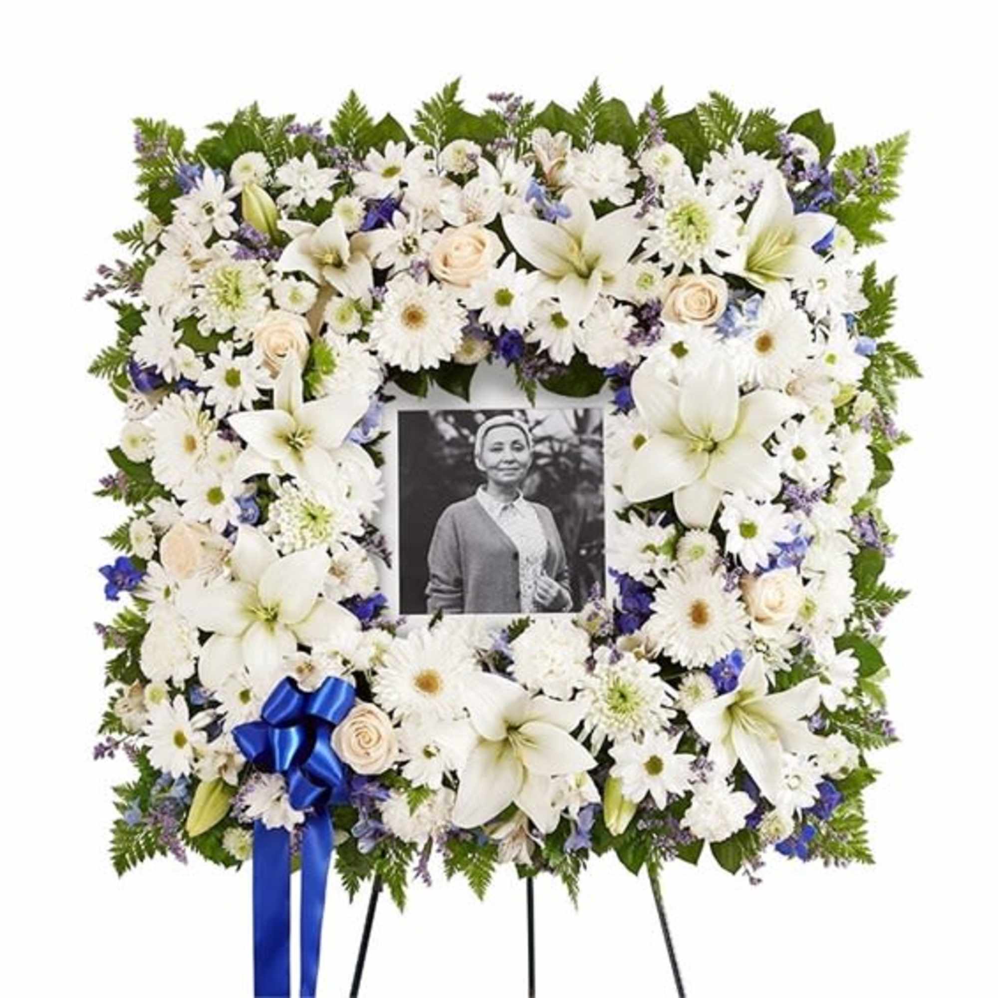 White floral funeral wreath with a photo in the center and blue ribbon