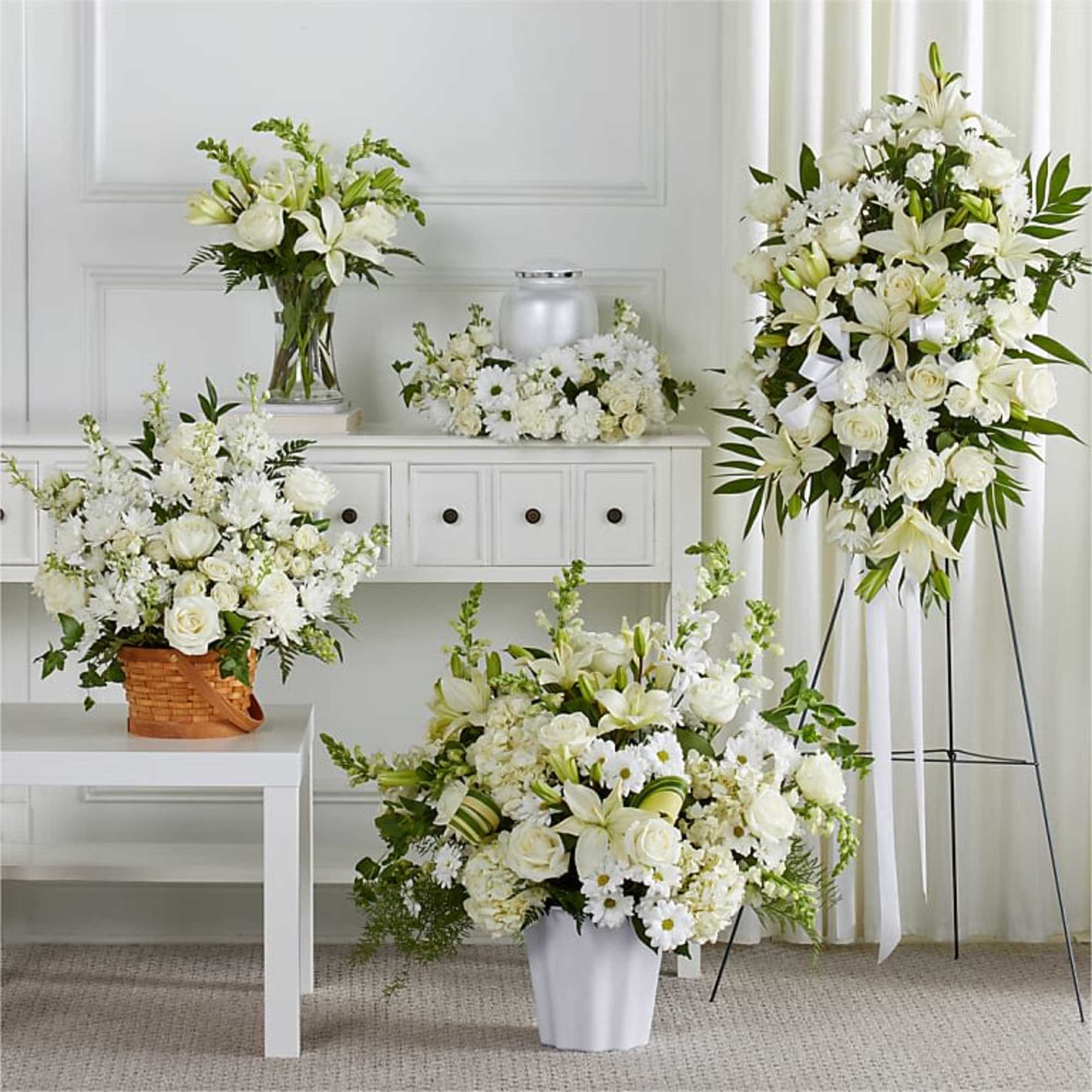 White floral arrangements in vases and a standing spray on display