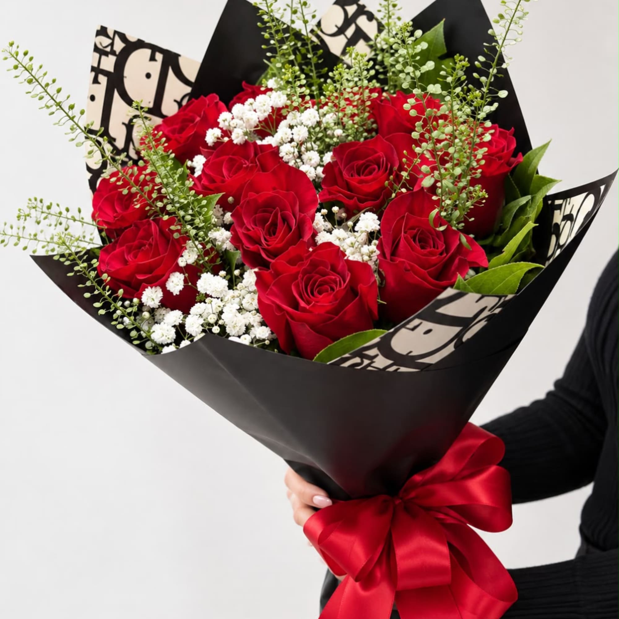 Bouquet of red roses with white baby's breath in black wrap and a red ribbon