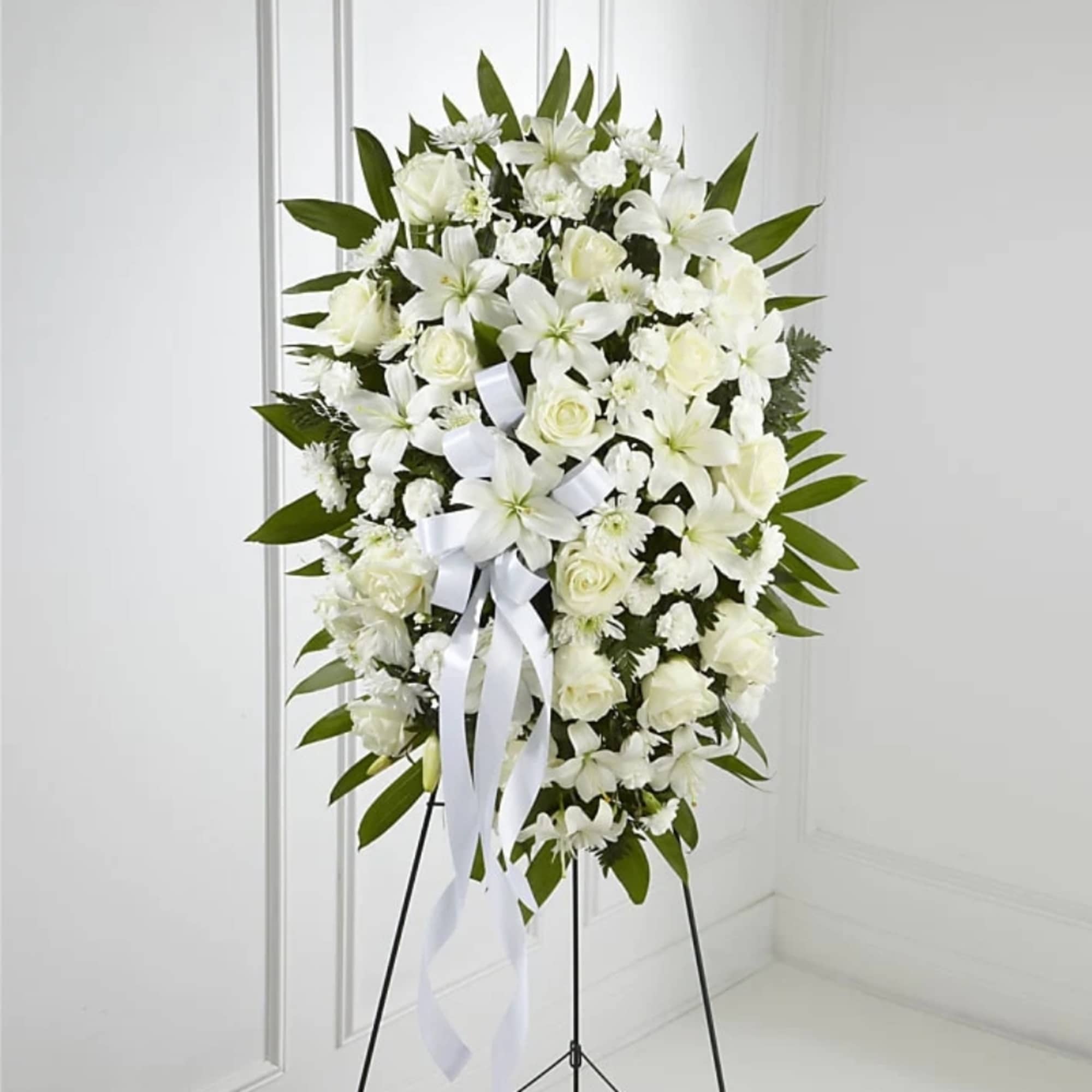 White funeral spray with lilies and roses on a stand