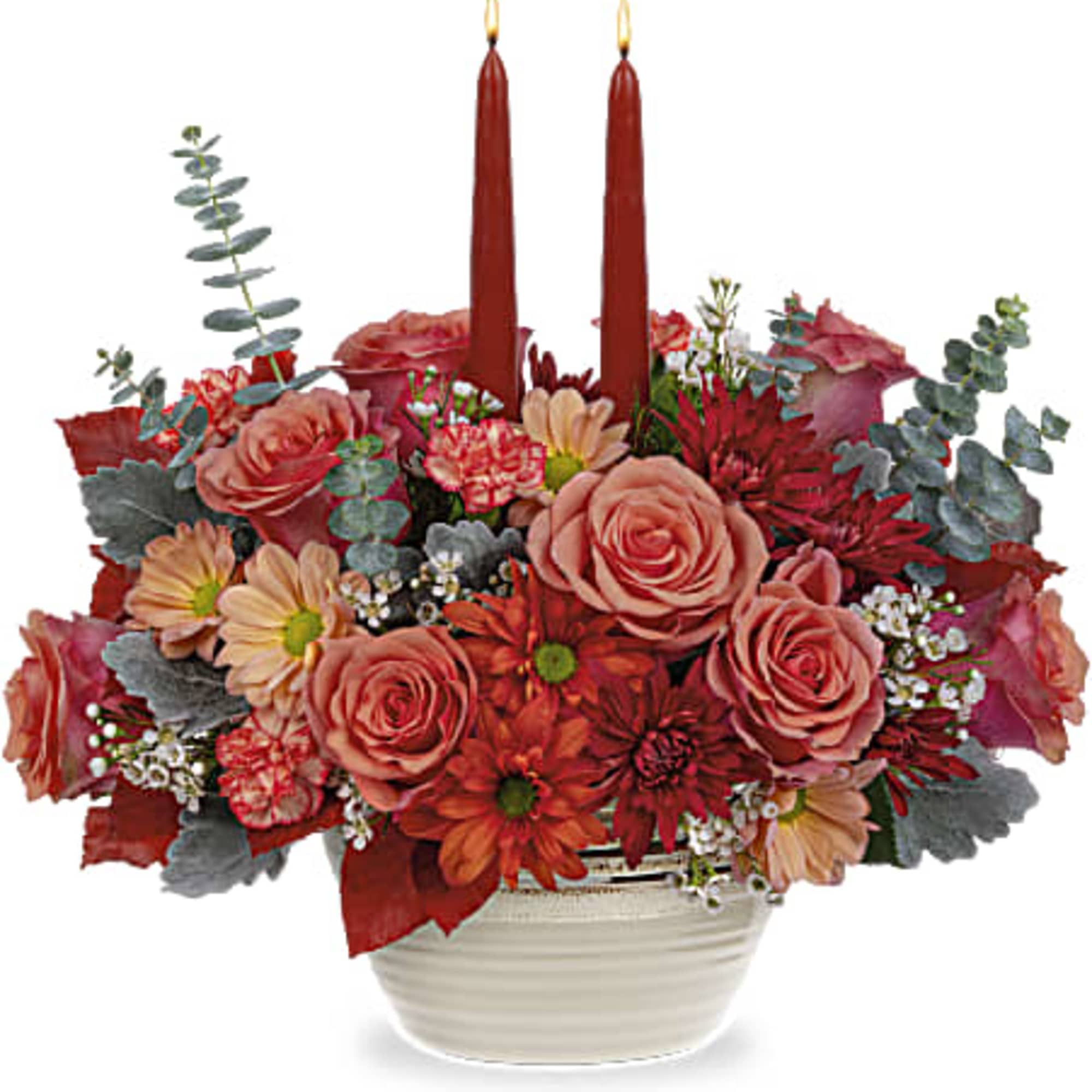 Red floral arrangement with two tall candles in a white bowl vase