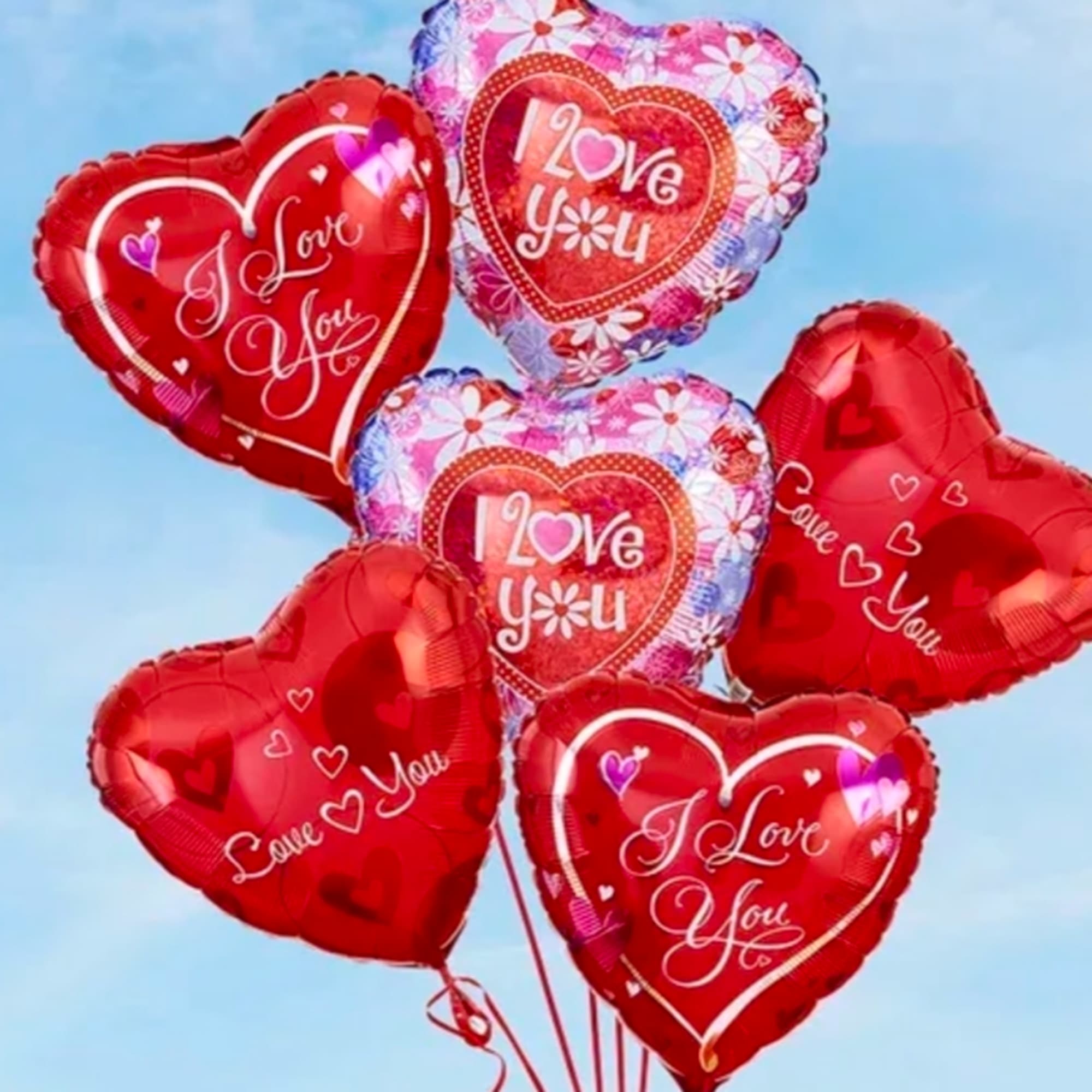 Cluster of heart-shaped red and pink balloons with love messages