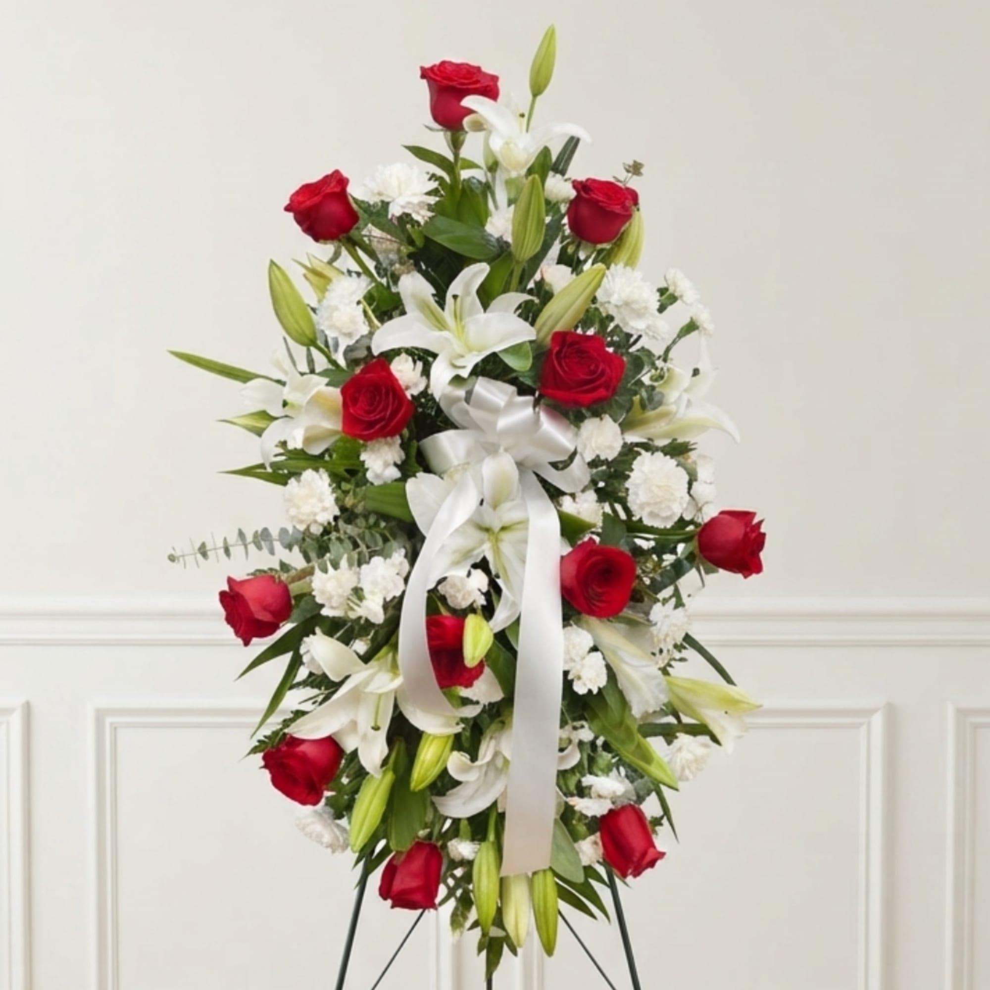 Standing floral spray with red roses, white lilies, and a white ribbon