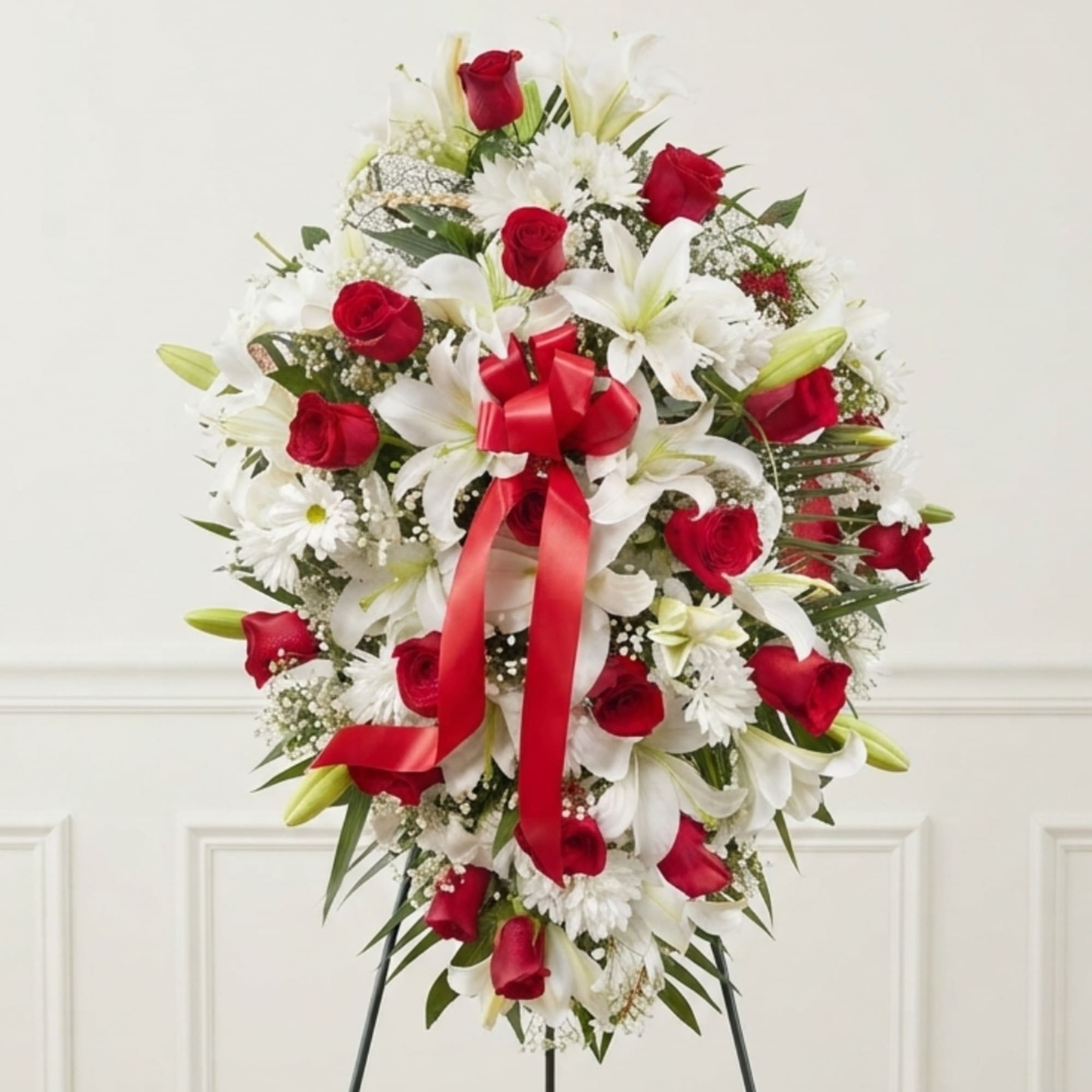 Heart-shaped wreath of red roses and white lilies with a red ribbon