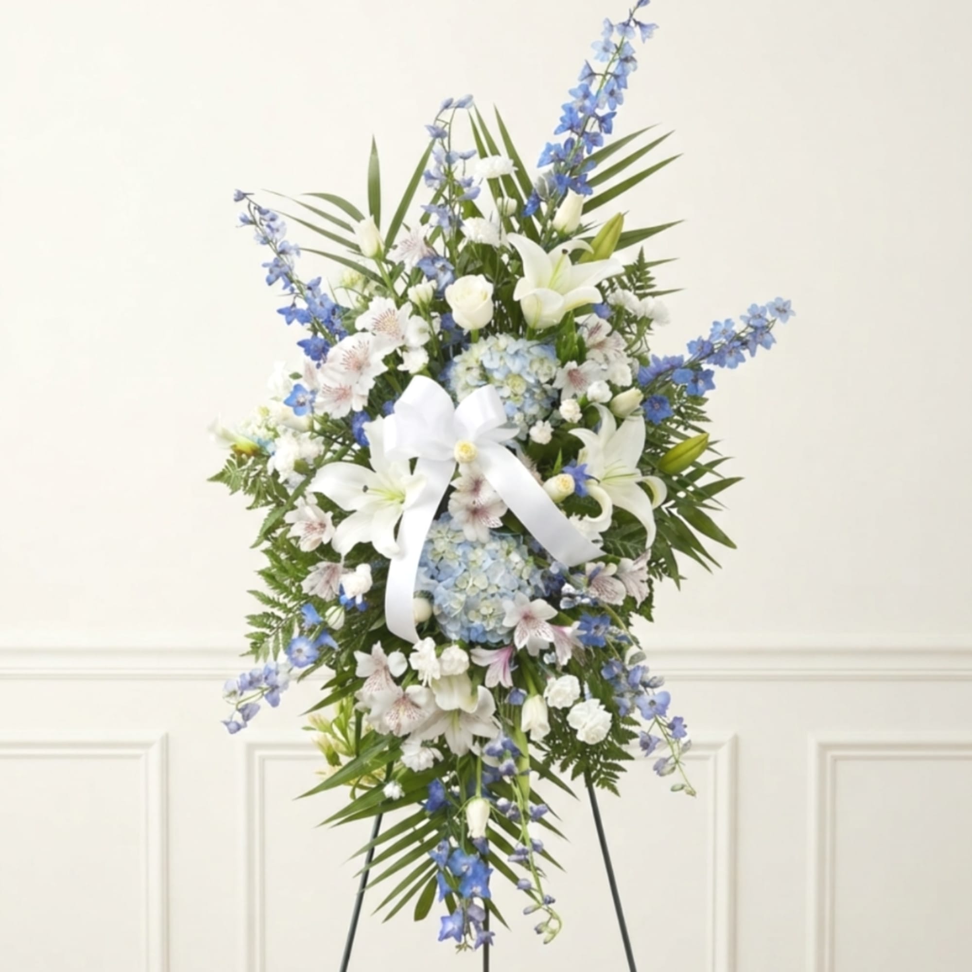 Tall blue and white floral standing spray with a white ribbon