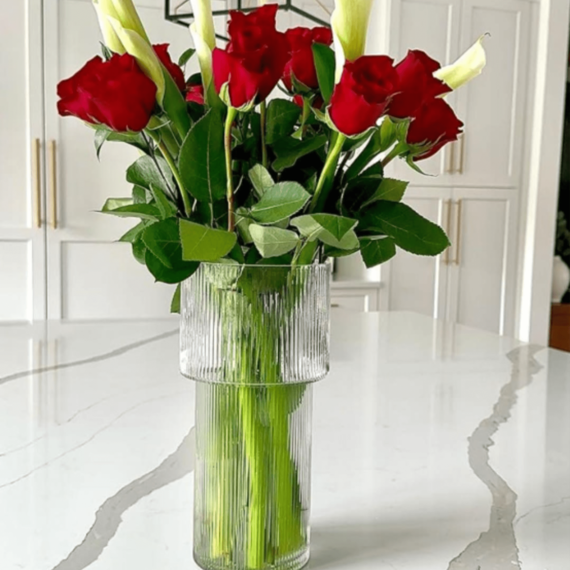 Tall white calla lilies rising above deep red roses create a striking