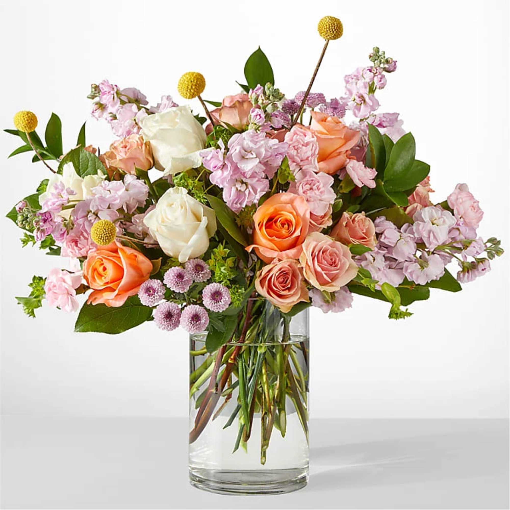 Mixed bouquet of roses and pink blooms in a clear glass vase