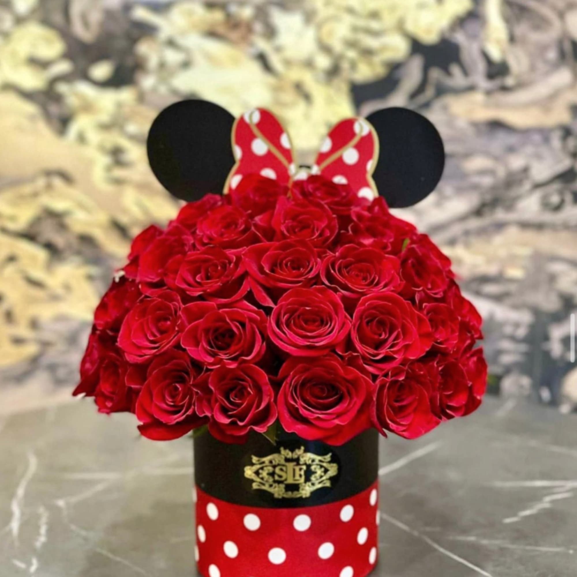 Red roses arranged in a Minnie Mouse-themed hat box with polka dots