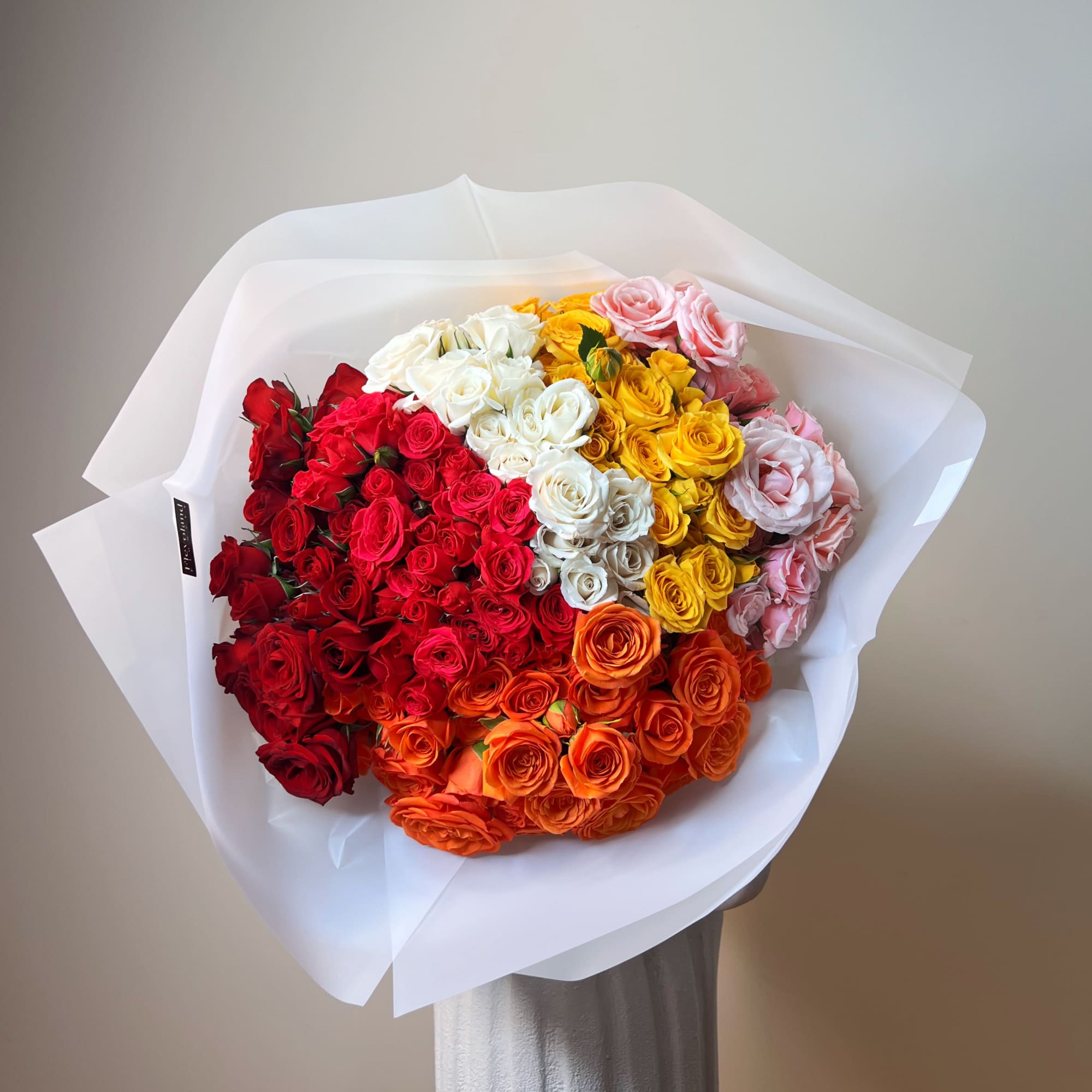 Large bouquet of multicolored roses wrapped in white paper