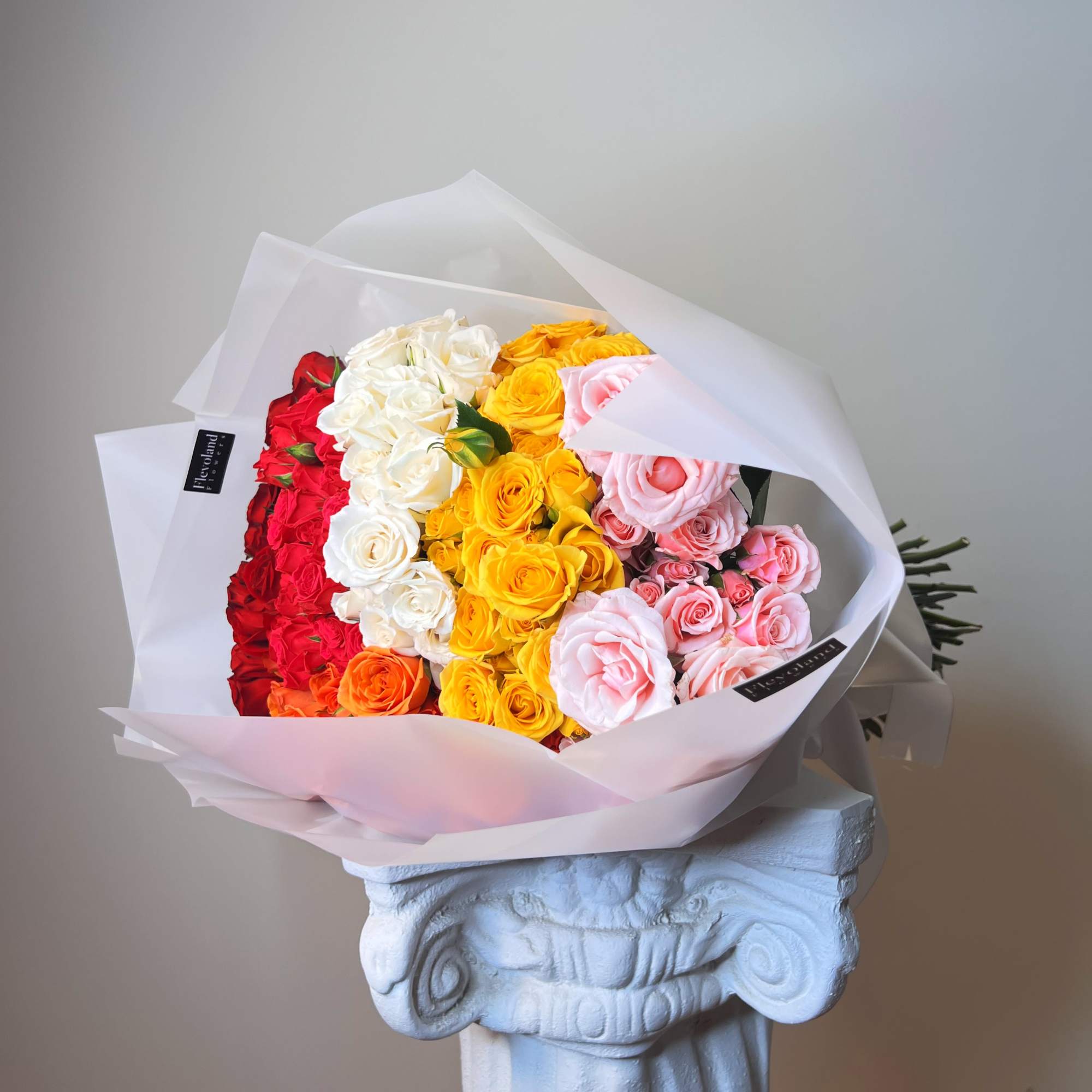 Bouquet of multicolored roses wrapped in white paper