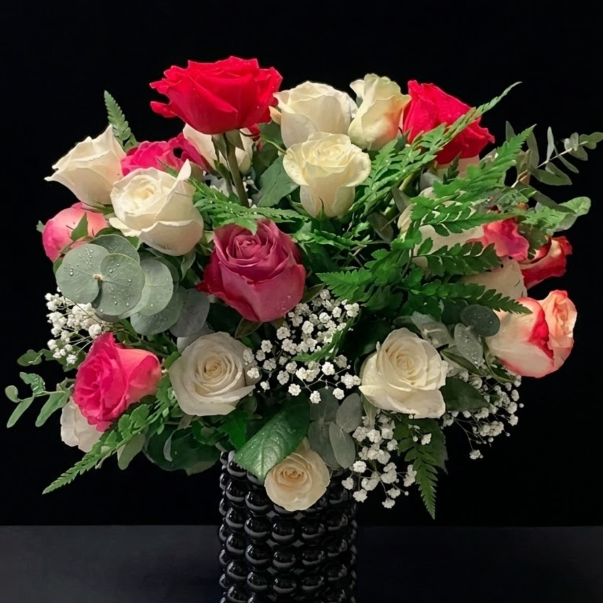 Bouquet of red, pink, and white roses in a black vase