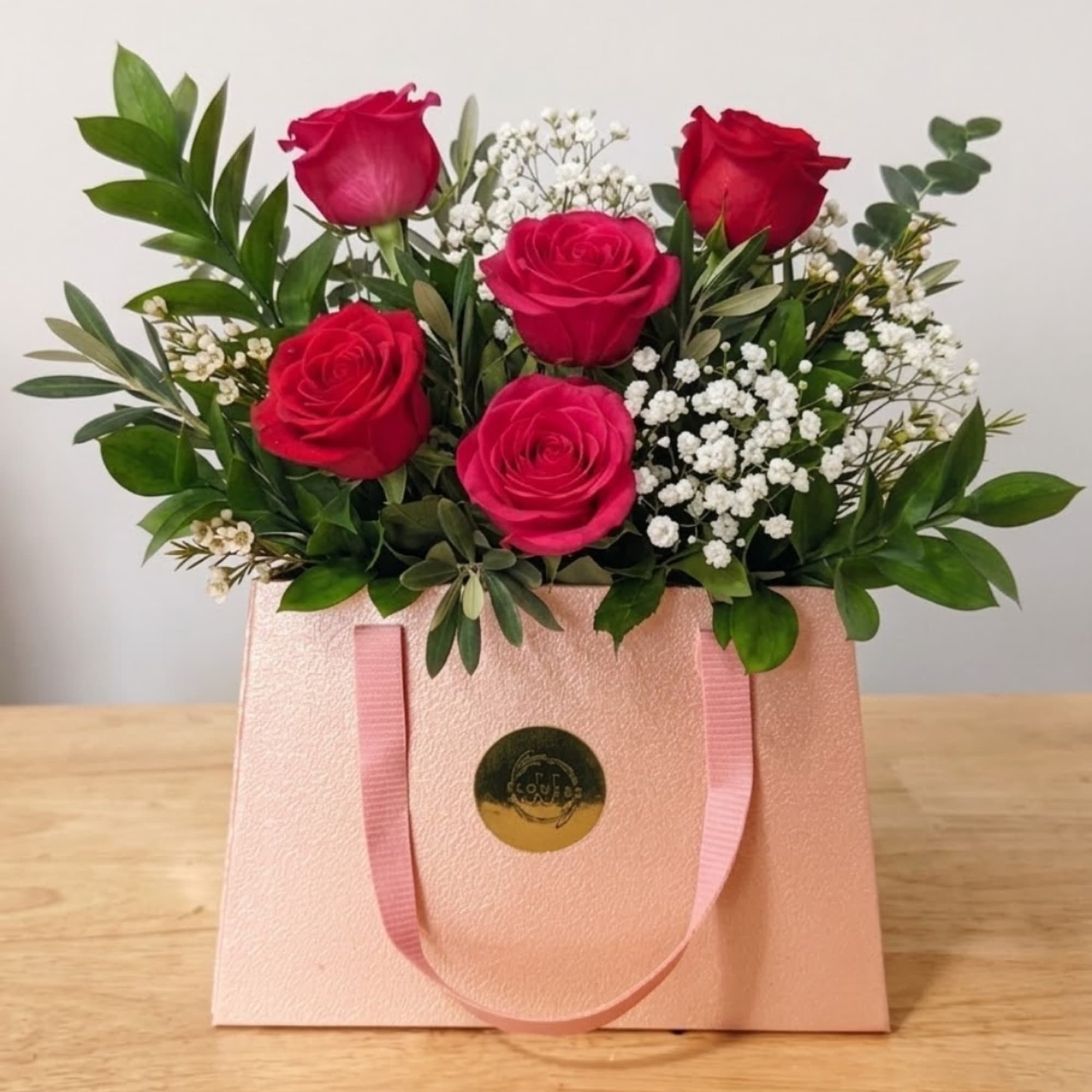 Pink roses with white baby's breath in a blush gift bag