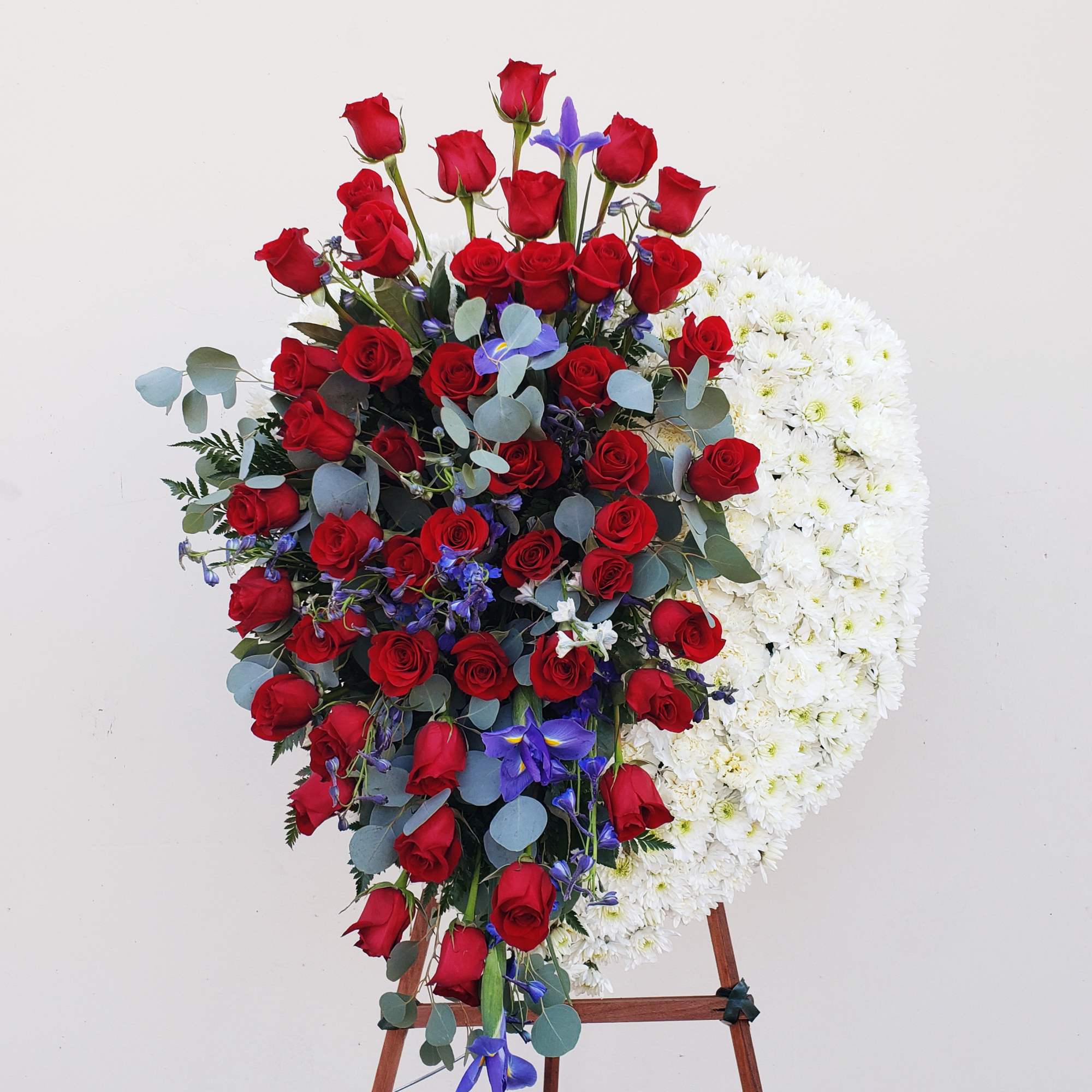 Standing floral spray of red roses and white flowers on an easel