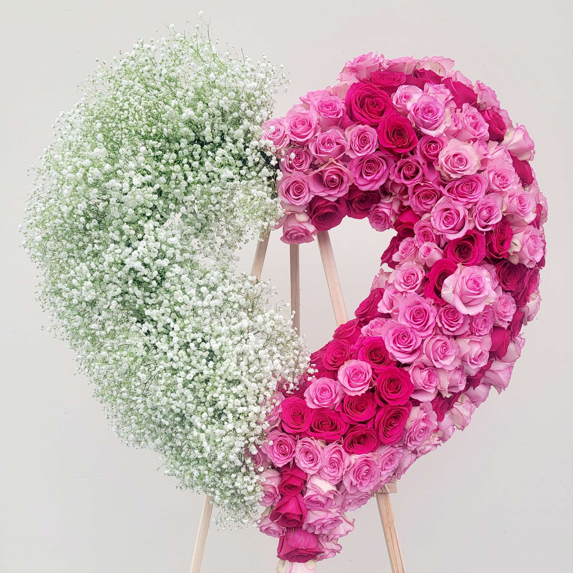 Heart-shaped floral display of pink roses and white baby's breath on an easel