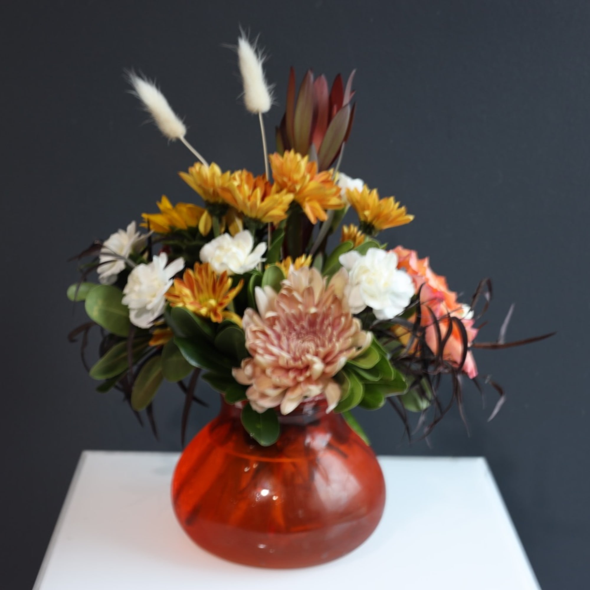 Mixed flower arrangement in an orange glass vase