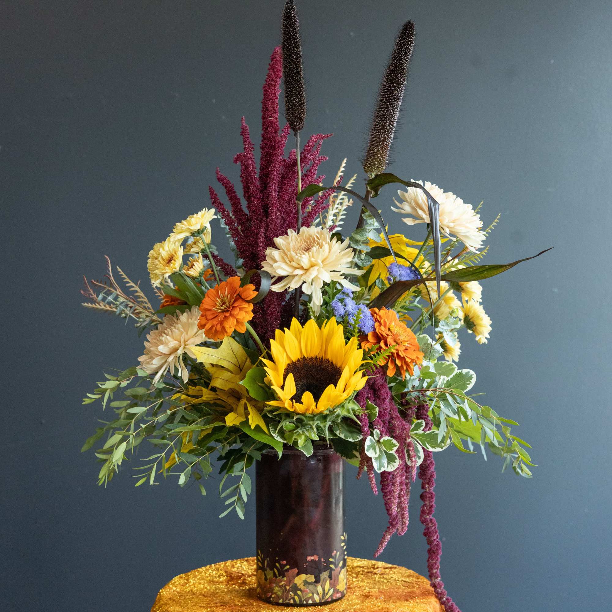 Mixed bouquet with sunflowers, chrysanthemums, and orange blooms in a dark vase
