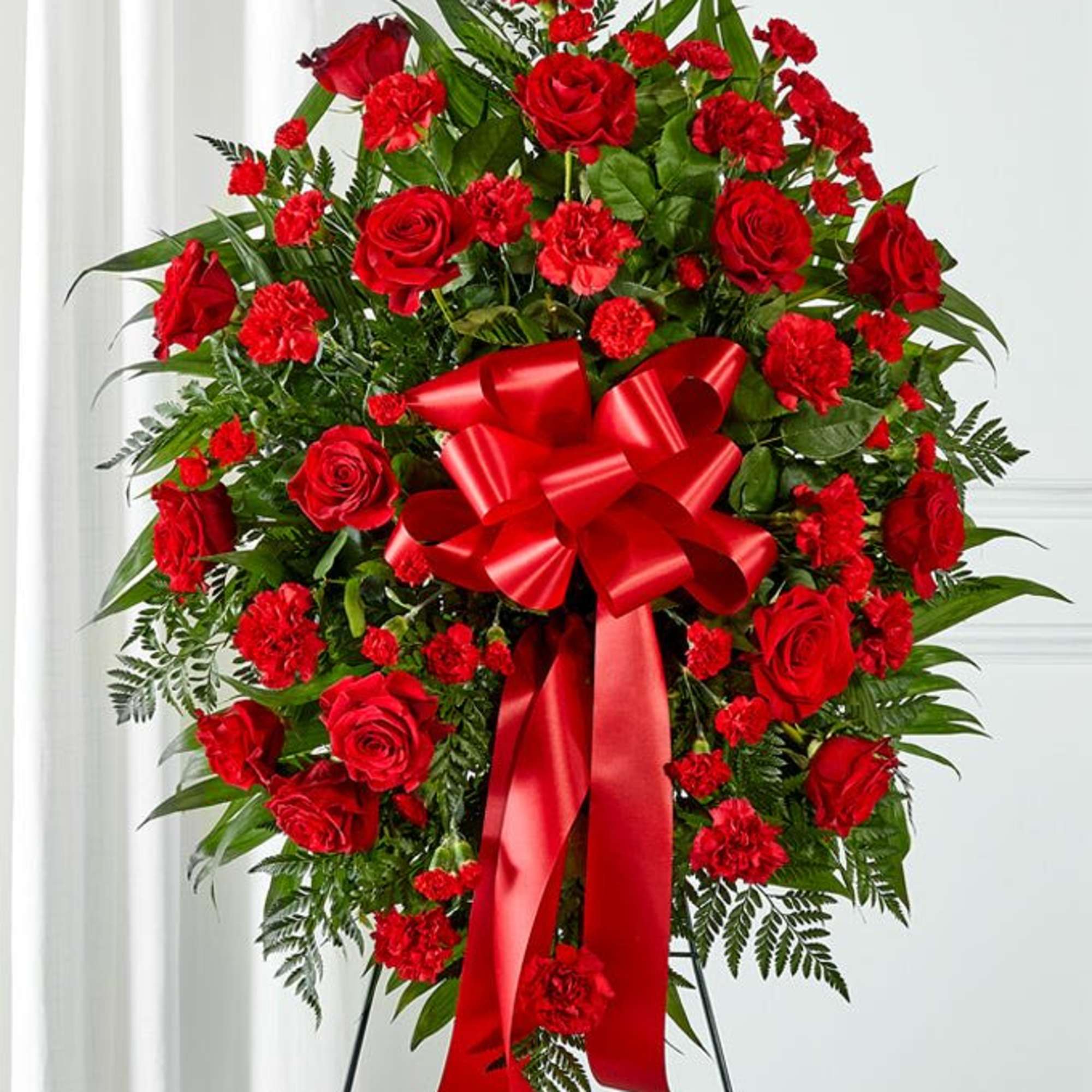 Red rose and carnation standing spray with a large red ribbon