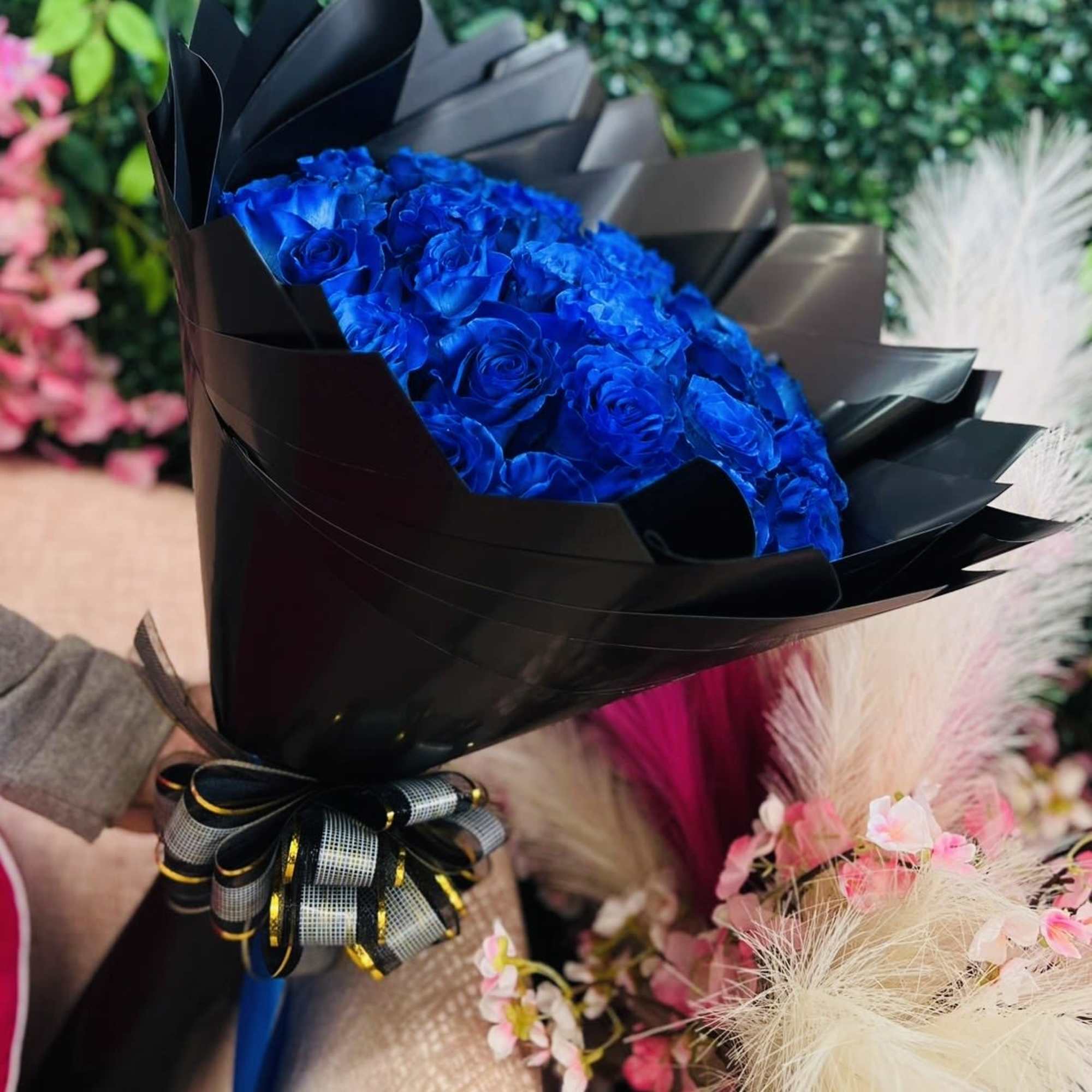 Bouquet of vivid blue roses wrapped in black paper with a ribbon bow