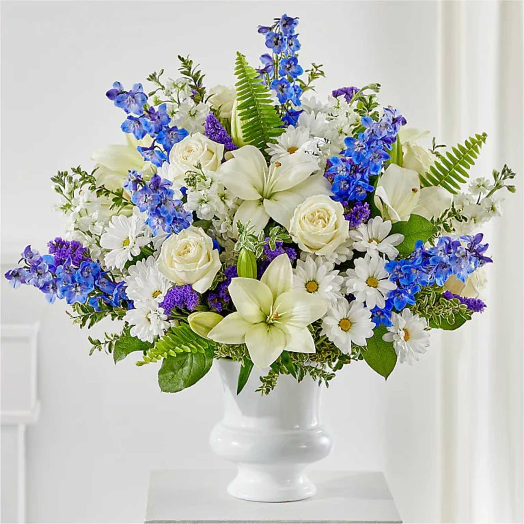 White and blue mixed flower arrangement in a white vase