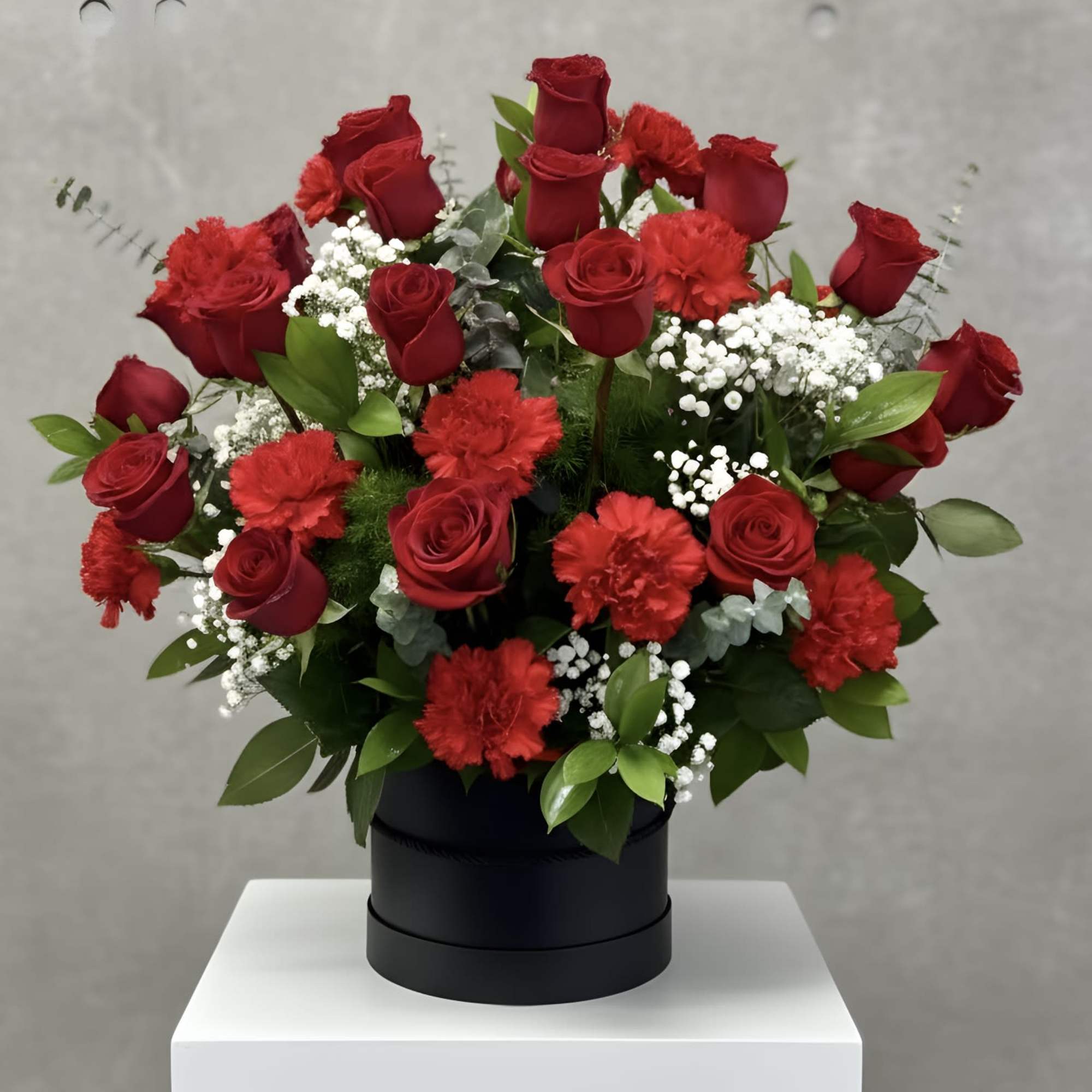 Red roses and carnations arranged in a black box