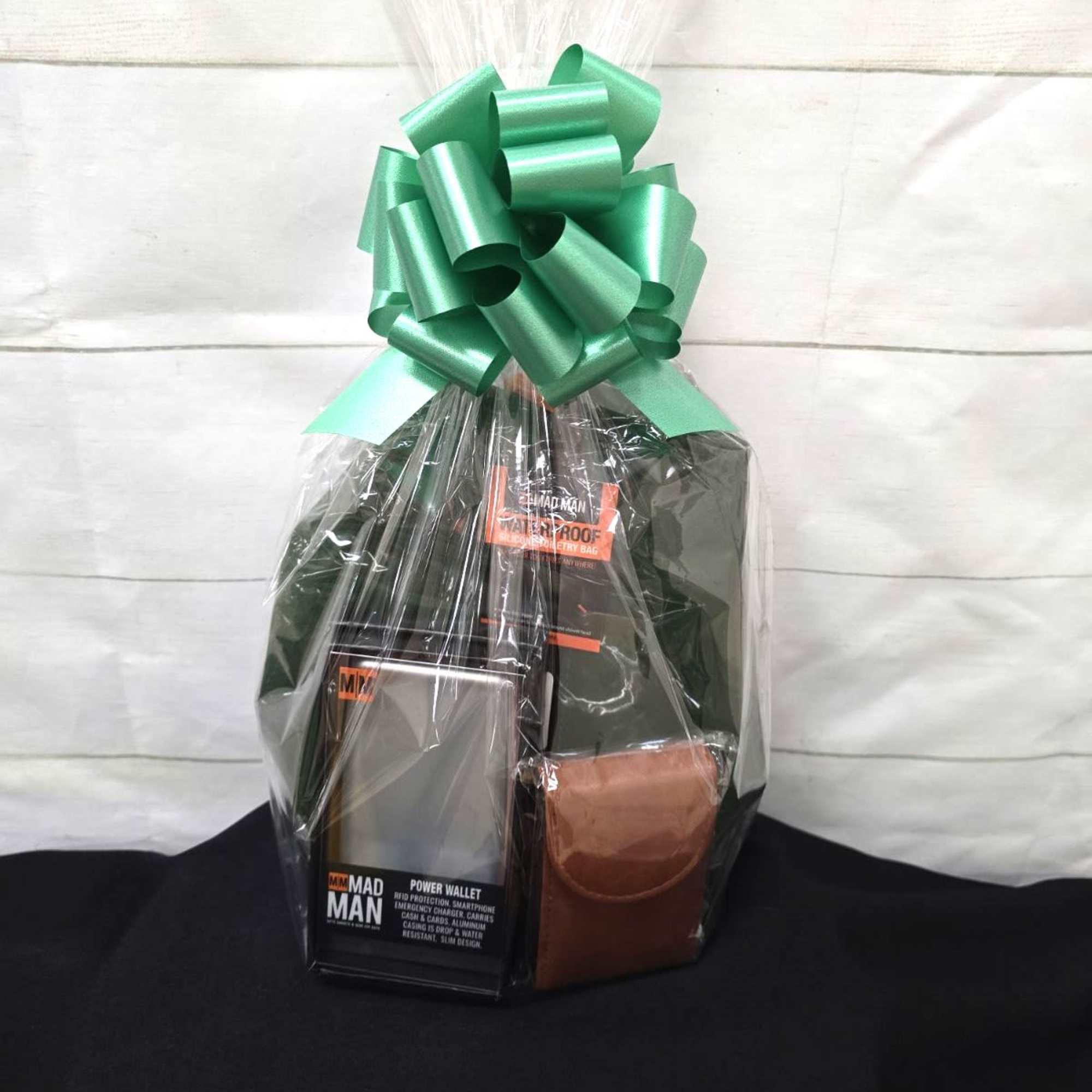 Cellophane-wrapped gift set with men’s accessories and a large green bow on top