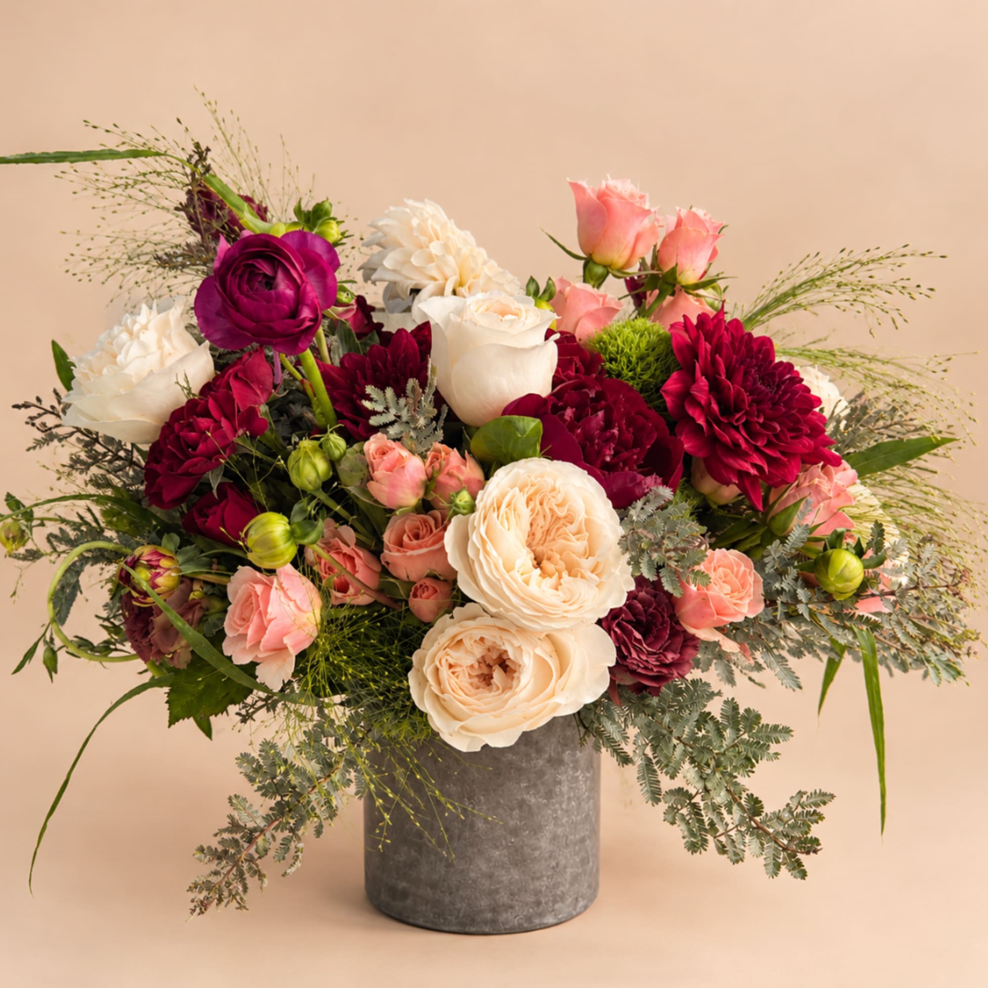 Mixed bouquet of roses, dahlias, and carnations in a gray vase