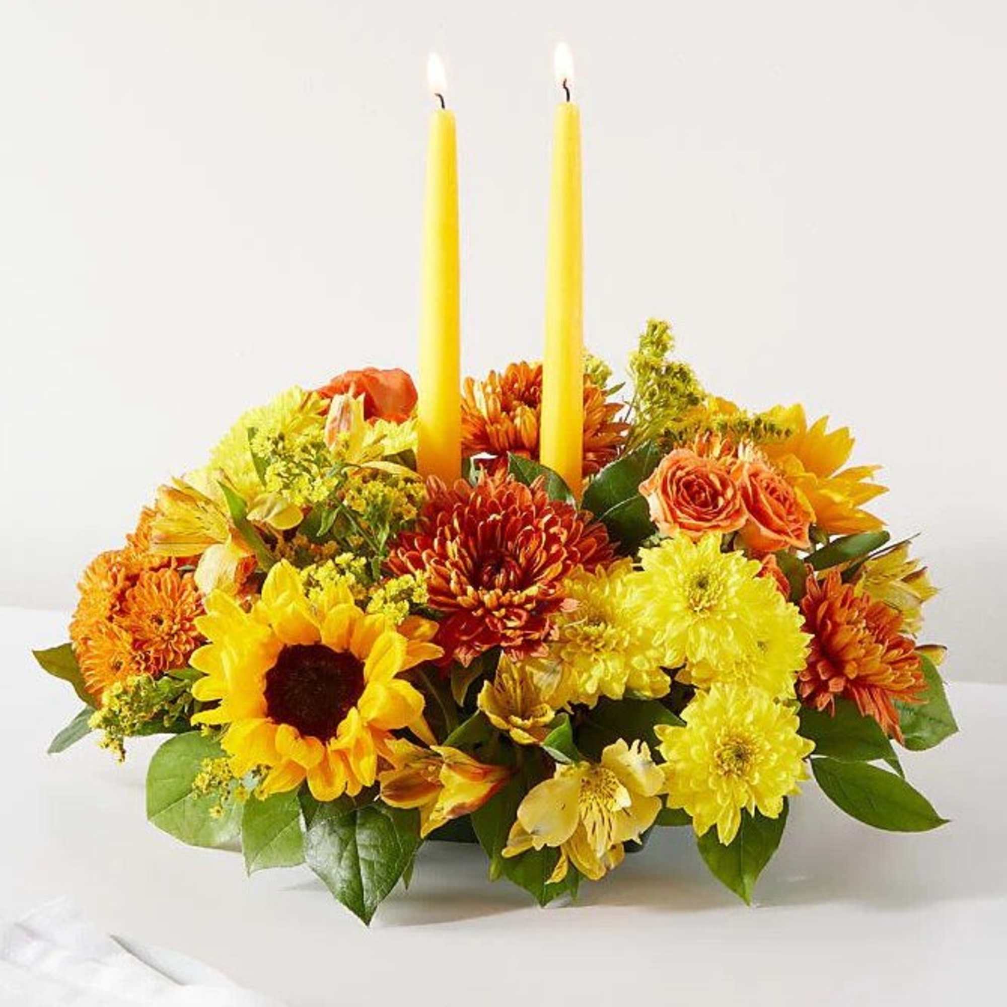 Yellow and orange floral centerpiece with two tall candles