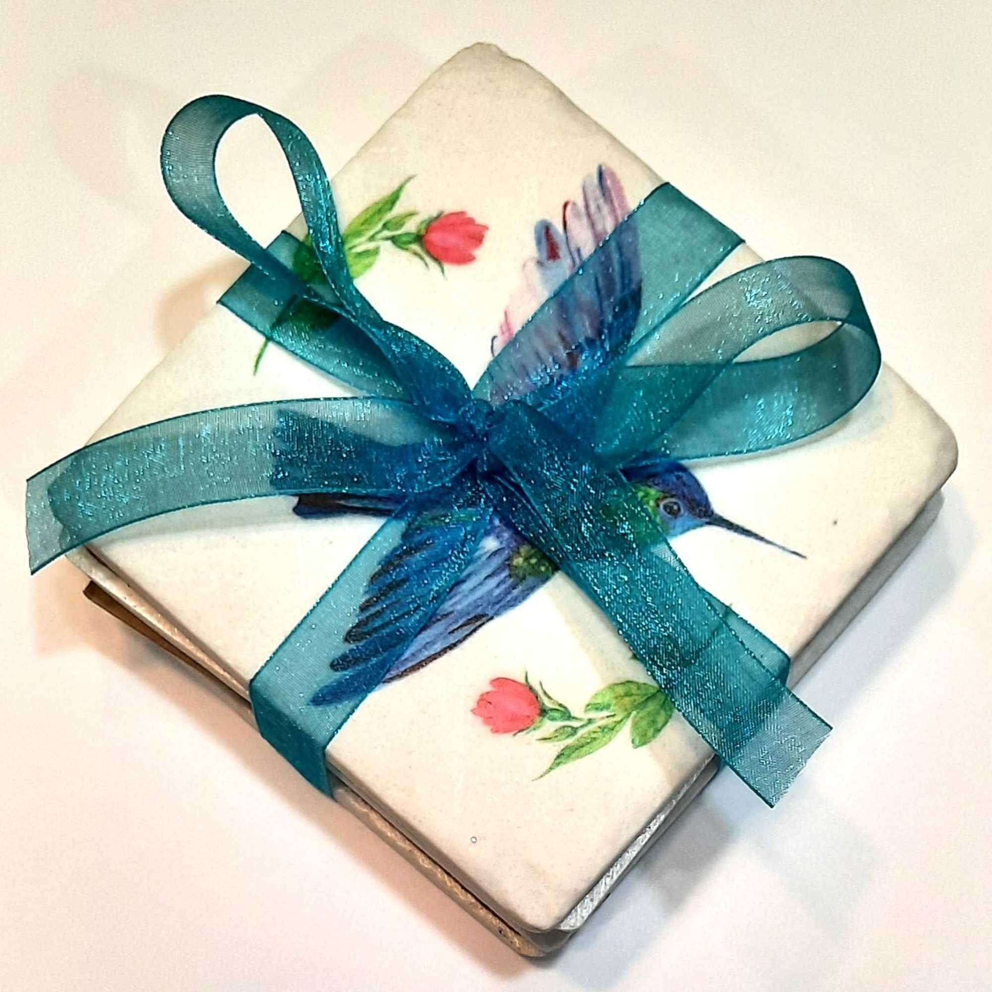 Decorative square gift box tied with a teal ribbon and hummingbird design